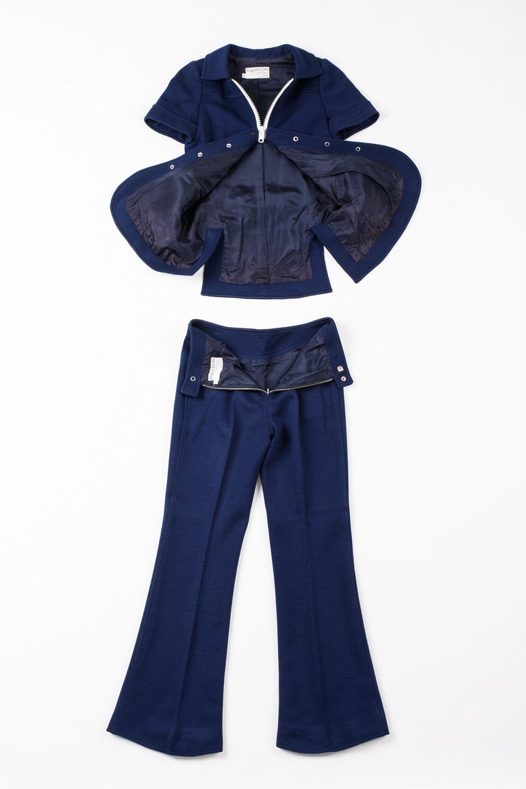 Circa 1972-1975

France

Rare André Courrèges Hyperbole trouser suit in navy blue jersey from the early 1970s. Fitted jacket numbered 0532248, short sleeves with folded collar, white plastic press studs and zip. Two flap pockets and crossed back