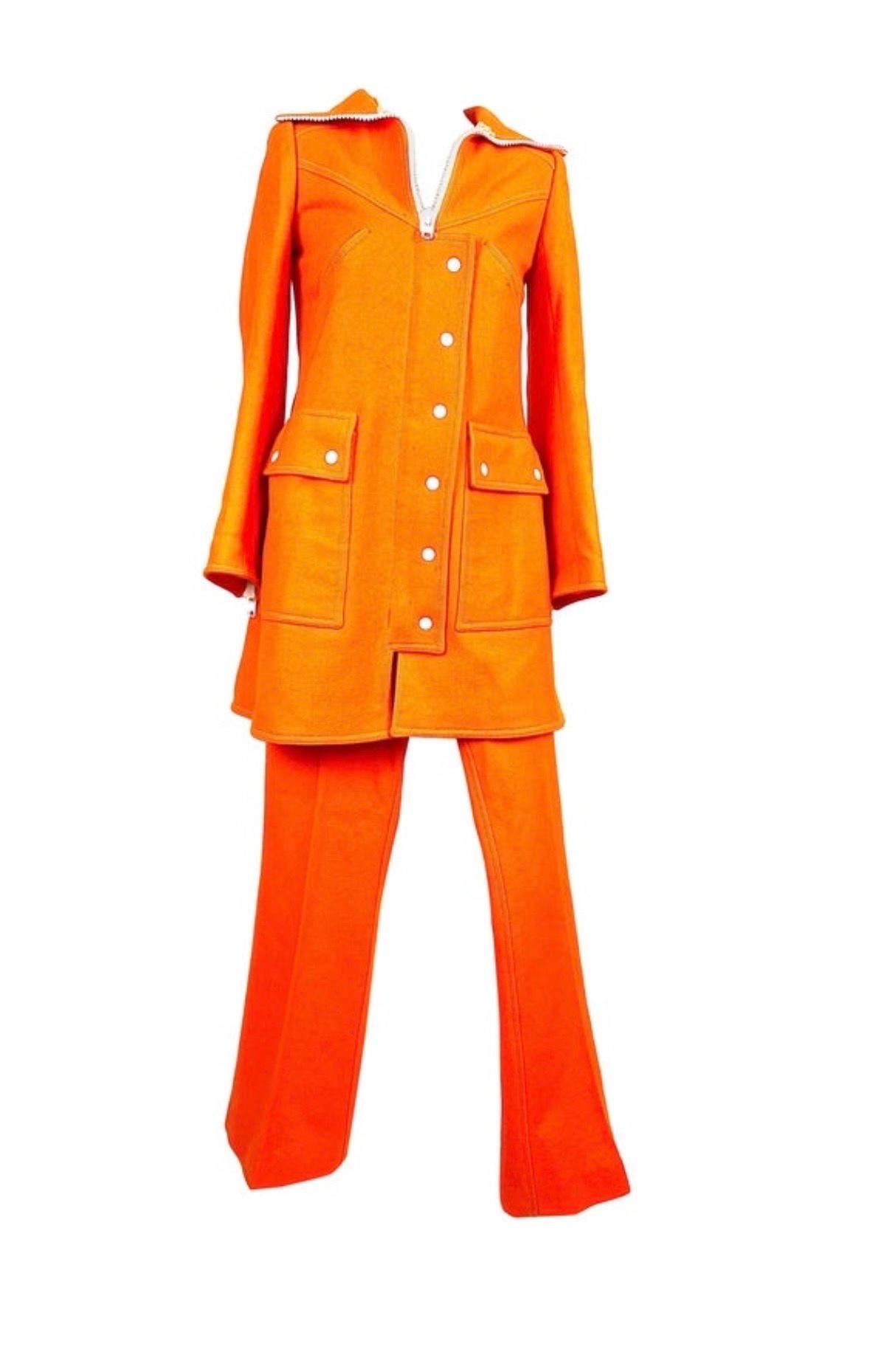 Vintage André Courrèges Hyperbole trouser suit numbered 0520940 from the 1970s.
In orange wool, fitted, pretty trucker collar with a long and imposing white zipper partly hidden by a press-stud flap.
2 raglan pockets on the chest.
2 large flap