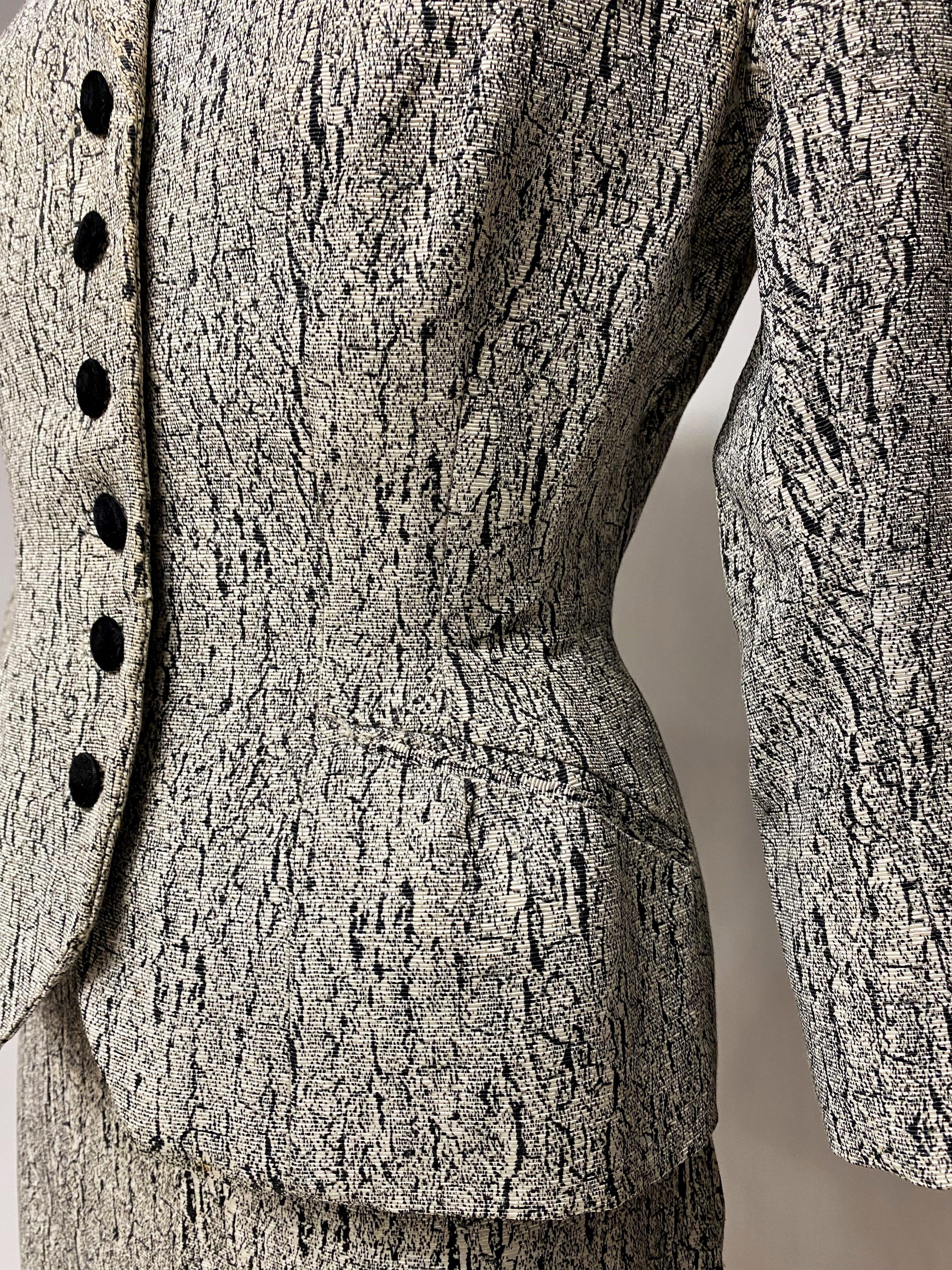 Circa 1947-1950

France 

Costume jupe non étiqueté Bar Haute Couture en faille de soie imprimée marbrée noire et blanche datant des années New-Look de Christian Dior. Veste à manches trois quarts, ajustée avec une forme rigide sur les hanches