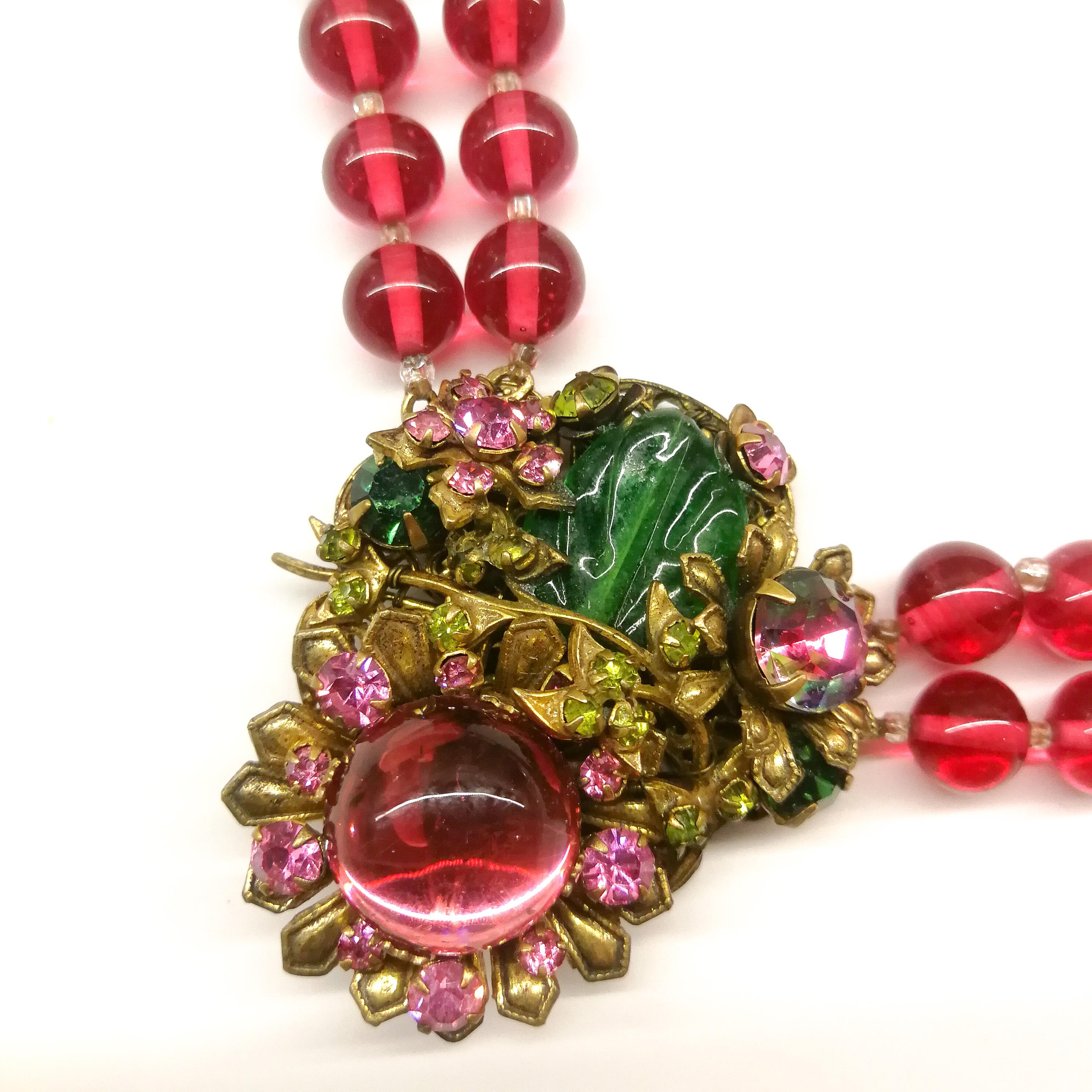 A beautiful, richly coloured necklace designed by Frank Hess for Miriam Haskell in cranberry and emerald glass and pink pastes, set in an antique gilded metal. Consisting of two rows of transparent cranberry beads, with a centre piece at the front