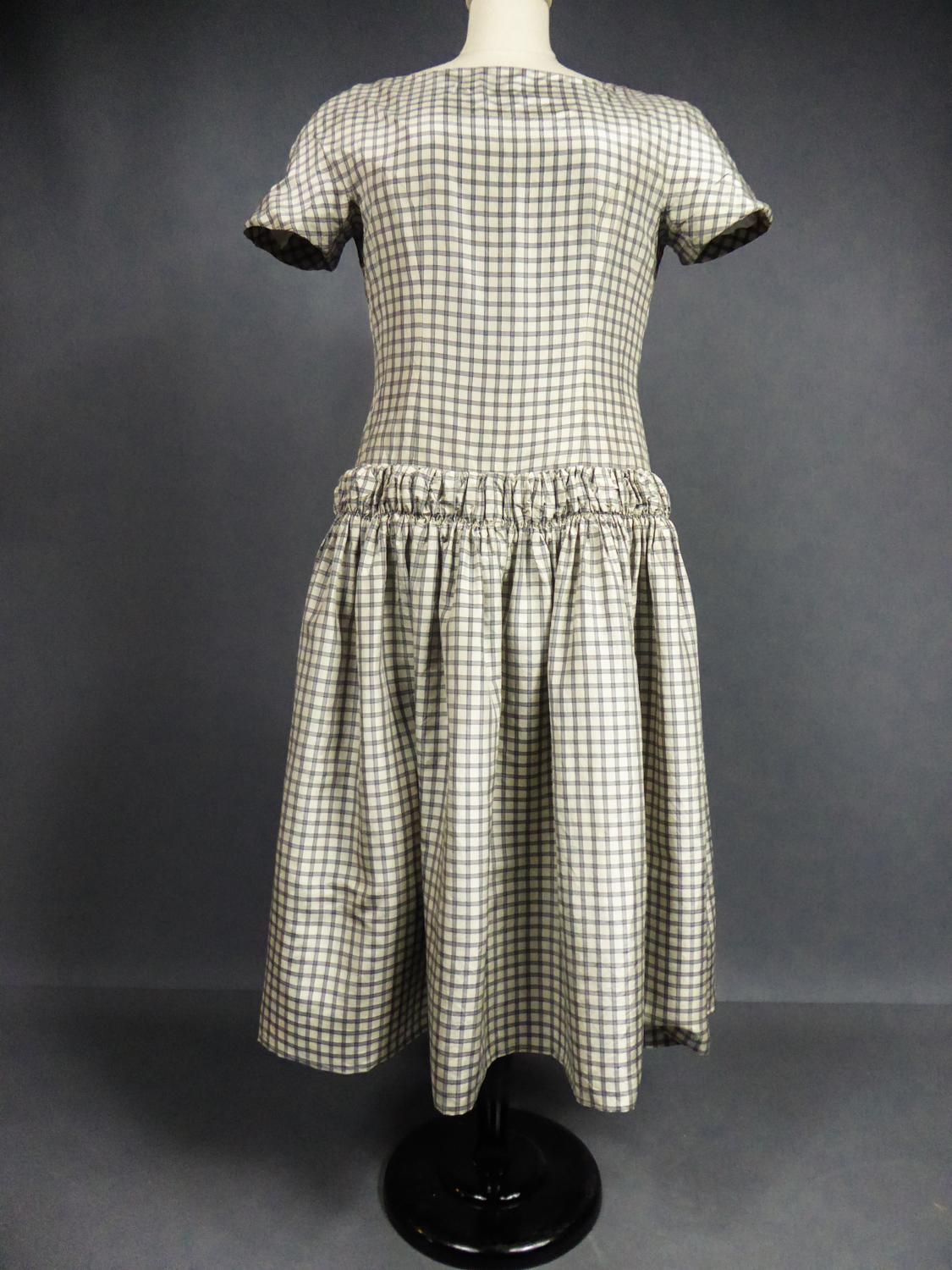 Circa 1955/1960
France

Historic dress from the Sac or Baby Doll line by Cristobal Balenciaga, Spanish master of Haute Couture numbered 55418 and dating from the years 1955-1960. Dress in very fine taffeta with gray and black checks on an off-white