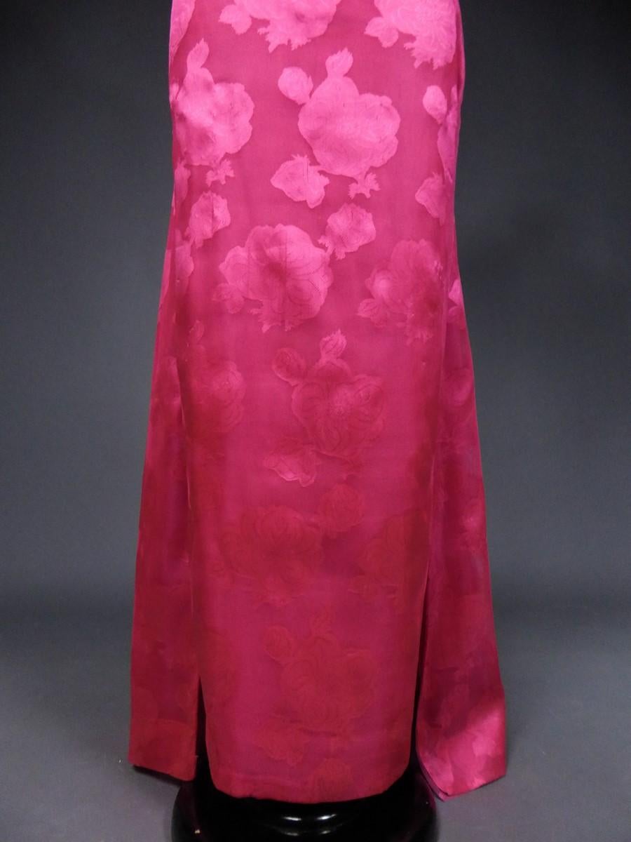 Circa 1957/1960
Paris France

A damask chiffon or brocade organza silk evening dress with large fuchsia blooming roses and rosebuds by Cristobal Balenciaga. Strapless finely pleated bodice, deep neckline and zipper in the back. Long sheer skirt