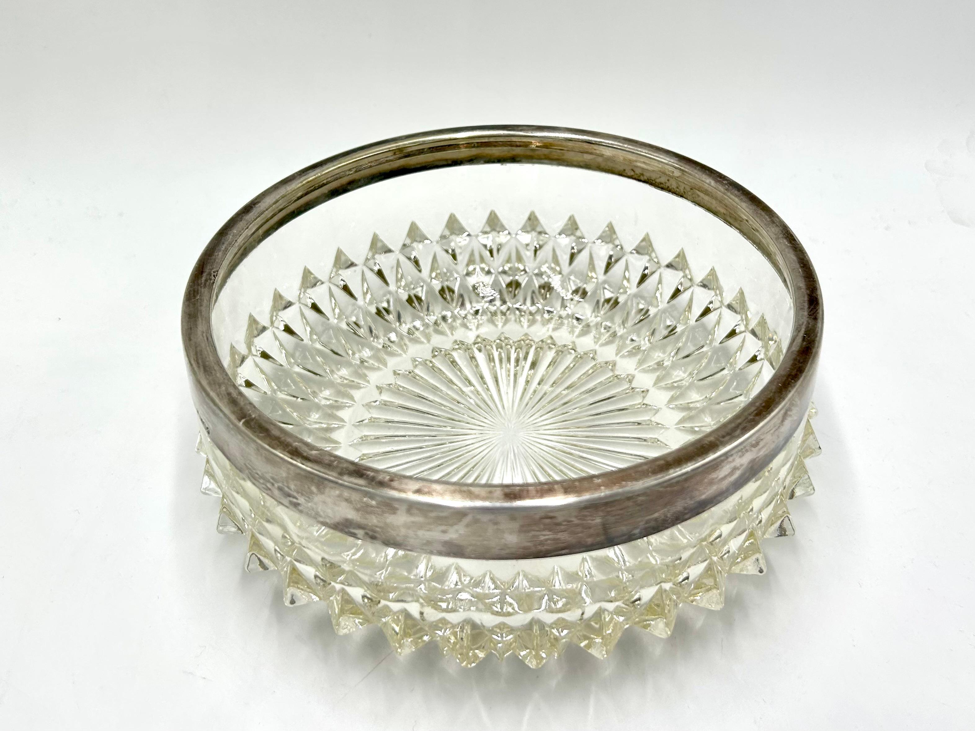 Un cuenco de cristal para dulces rematado con un anillo plateado.

Muy buen estado sin daños

Medidas: altura 8 cm

diámetro 20 cm.