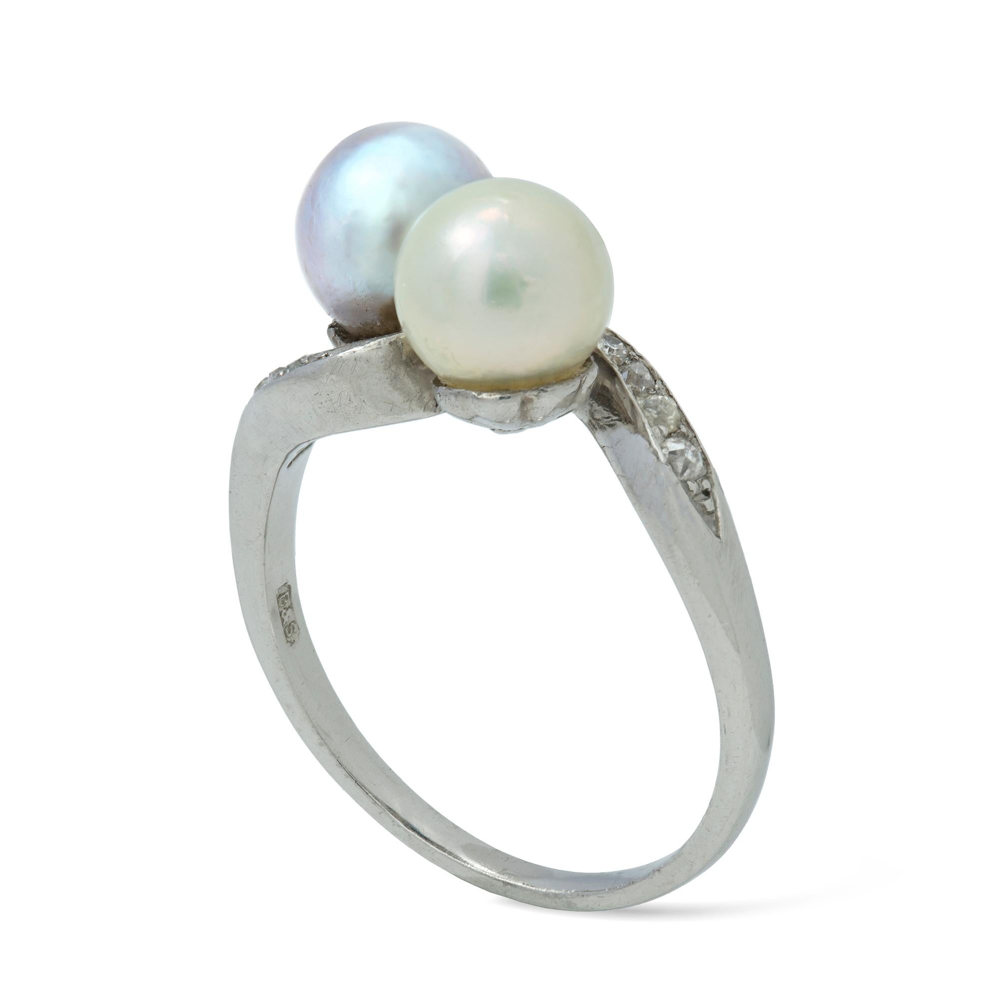 A cultured  pearls and diamonds cross-over ring, with one white and one purple cultured pearl diagonally set between curved diamond shoulders, with tapering D-Section shank all in platinum, later hallmarked London, 2012, bearing the Bentley&Skinner