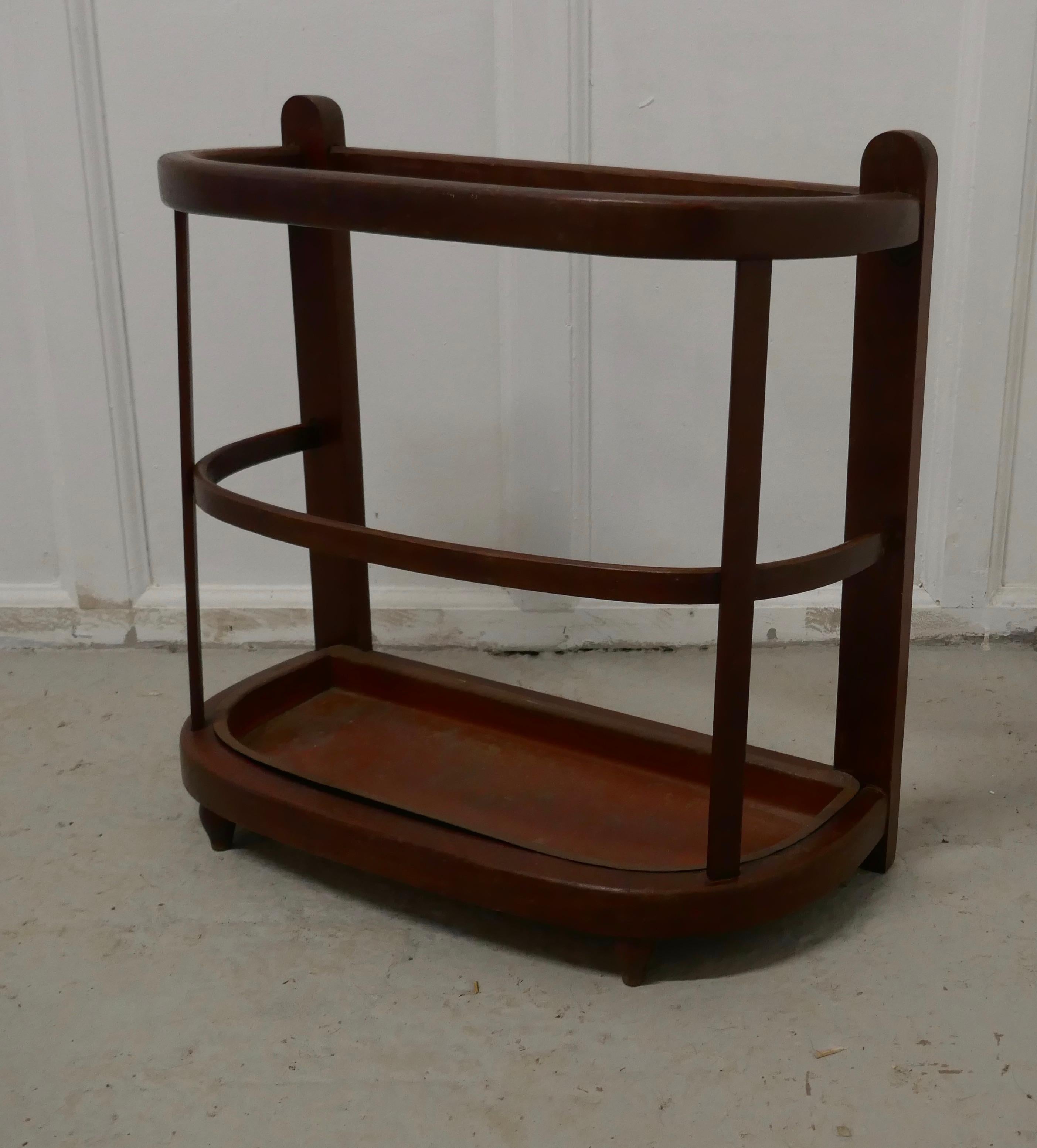 A curved French stick stand or umbrella hall stand

The stand is made to stand against a wall, the stand is in beech with a curved rail to the front, it comes with its original metal drip tray.
The stand will hold both walking sticks or umbrellas