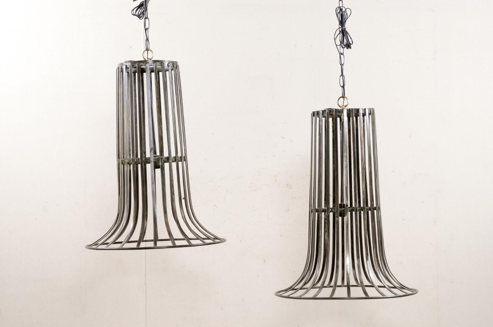 These custom pair of tall hanging metal light fixtures have been created by re-purposing a pair of French vintage iron baskets. This pair of chandeliers are comprised of a vintage metal barrel/basket from France, with iron caged body flipped upside