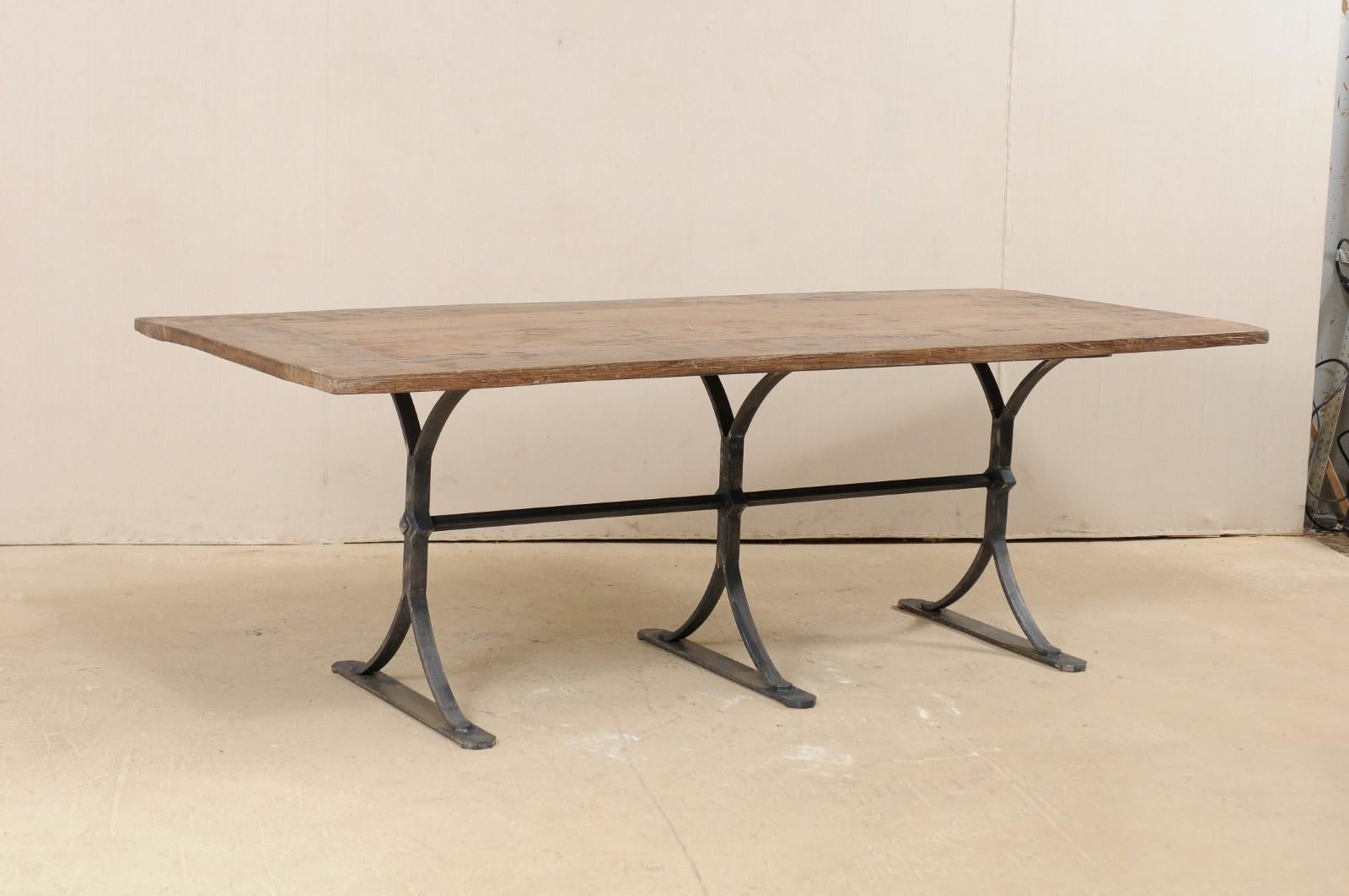 A Spanish table of old reclaimed wood with custom iron base. This 7.5 foot long dining table features a rectangular-shaped wood top, of old reclaimed oak and chestnut from Spain, resting upon a custom iron three-leg iron base. Both the wood, and