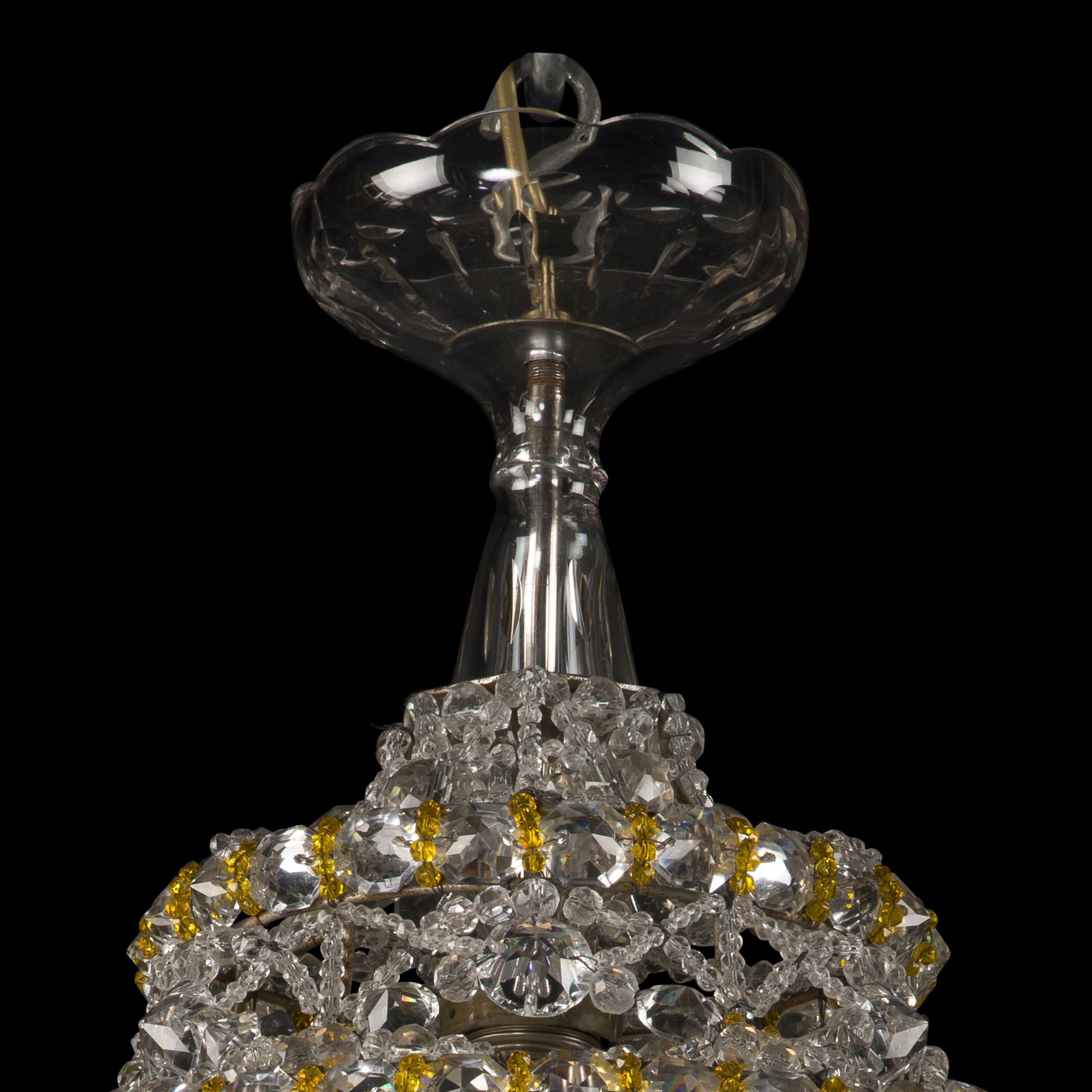 A cut-crystal hexagonal shaped lustre chandelier.

This unusual chandelier has a hexagonal shaped body formed of rule and octagonal cut drops, with faceted spheres and rosettes linked by chains of amber colored glass beads above a gallery fitted