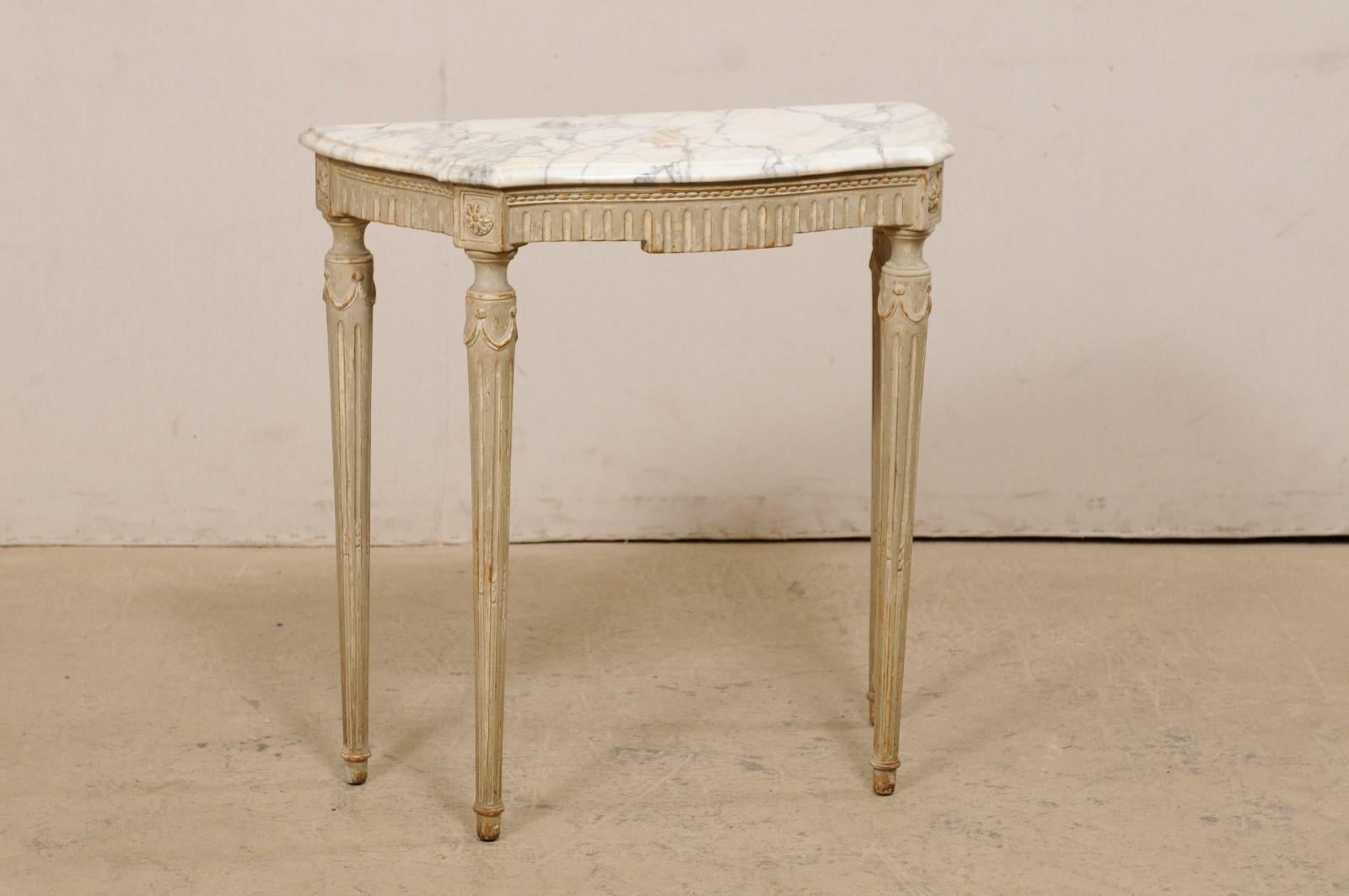 A French small-sized carved-wood console table, with it's original marble top, from the late 19th to early 20th century. This antique table from France retains it's original white marble top with gray veining, which is flat along the backside (so
