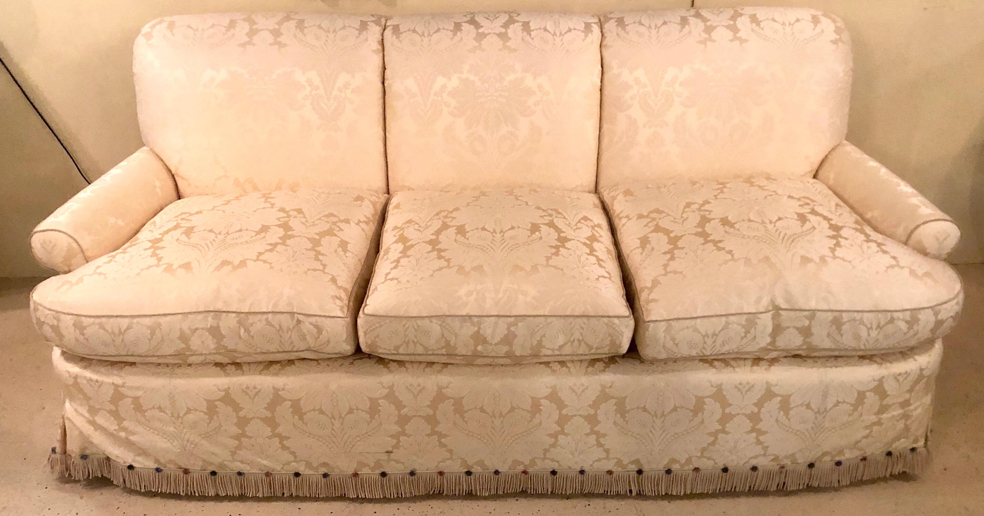 A damask finely upholstered couch with two cushions. This fine custom quality sofa or couch is simply stunning. The breathtaking upholstery with a frilly bottom and matching pillows. In very fine condition from a Bronxville estate.