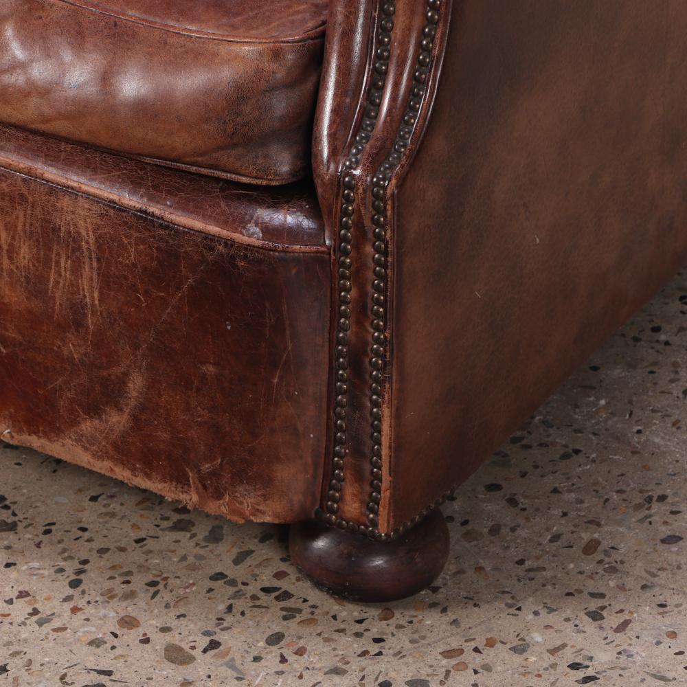 The chair features a tall, subtly curved wingback profile with gently flared arms and a deep, comfortable seat—hallmarks of Scandinavian design from the era. Supported by wooden bun feet, it combines elegance, comfort, and craftsmanship in equal