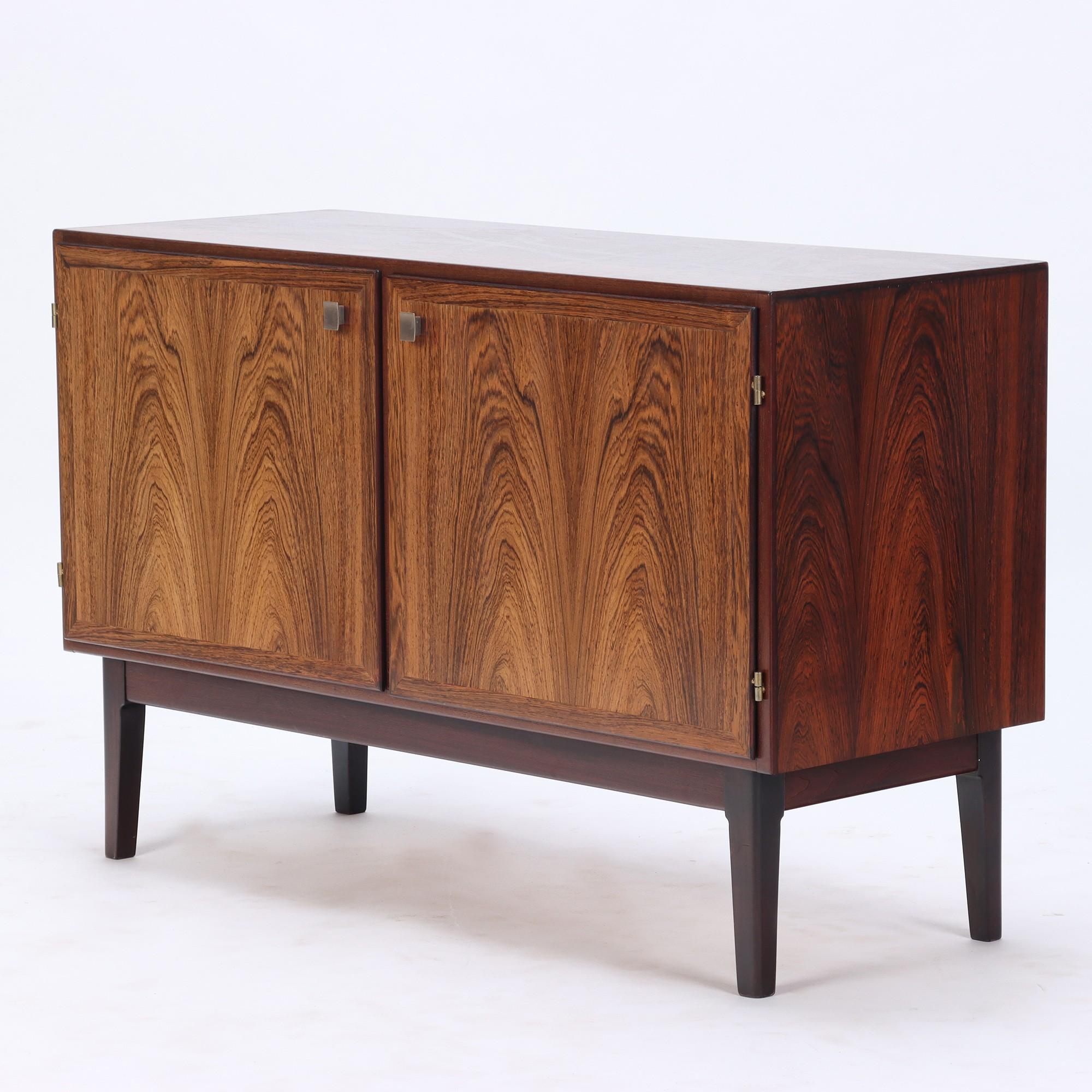 A Danish Mid Century Modern two door rosewood cabinet circa 1960. Featuring brushed metal door handles, two interior shelves, and bookmatched fronts. Perfect for use as a media cabinet, credenza, or small buffet server.