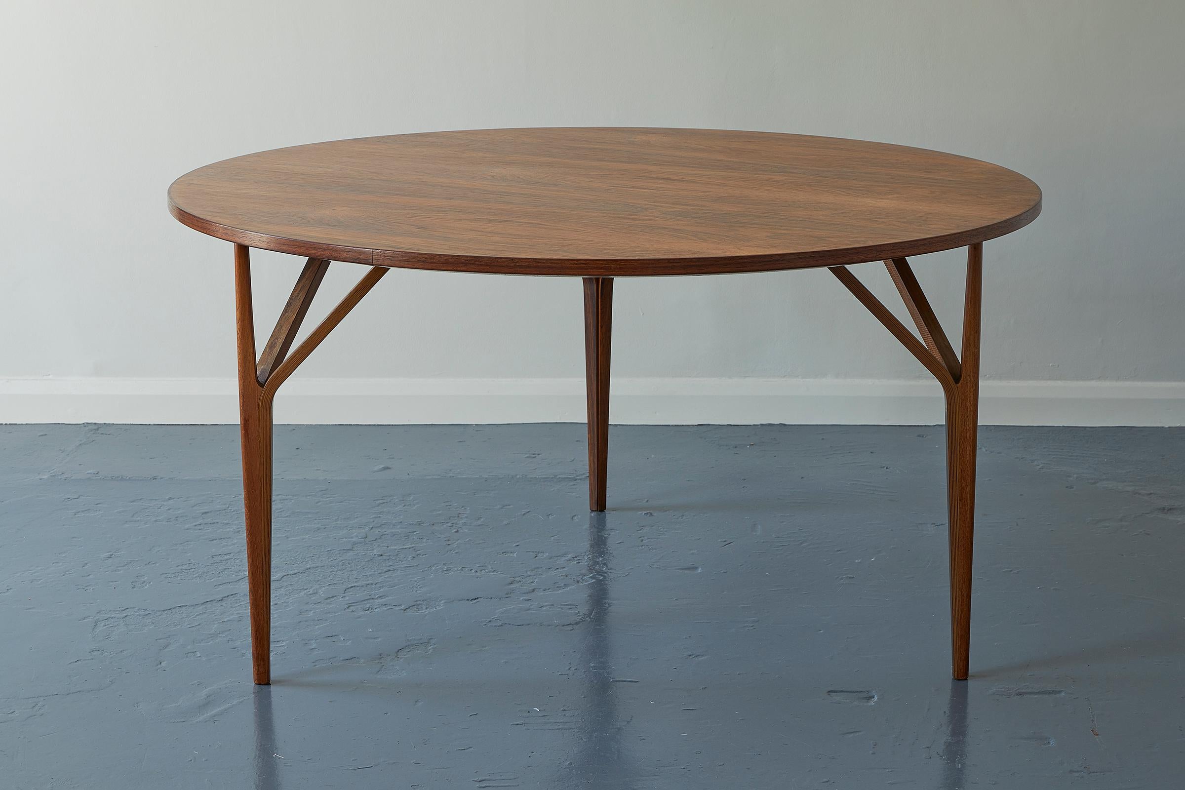 A Danish mid-20th century vintage rosewood dining table, circa 1960s, of circular shape, with a mirrored top, raised on three strut supports.