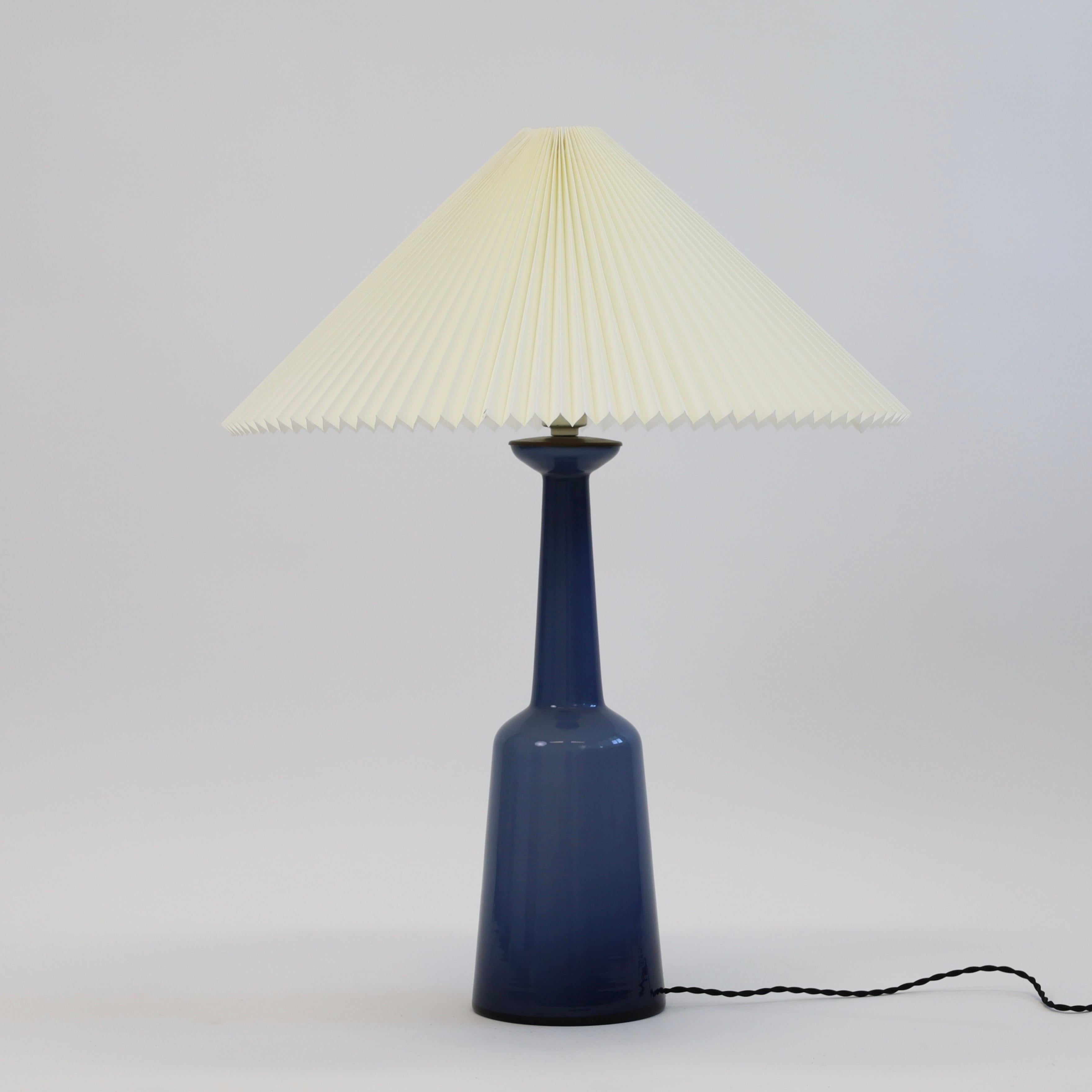 A sizeable 1950s glass table lamp by Kastrup Glasvaerk - almost floor size. Remarkable deep night blue and an eye-catching piece for a beautiful space. 

* A blue glass table lamp with a brass top and a pleated white fabric shade
* Manufacturer: