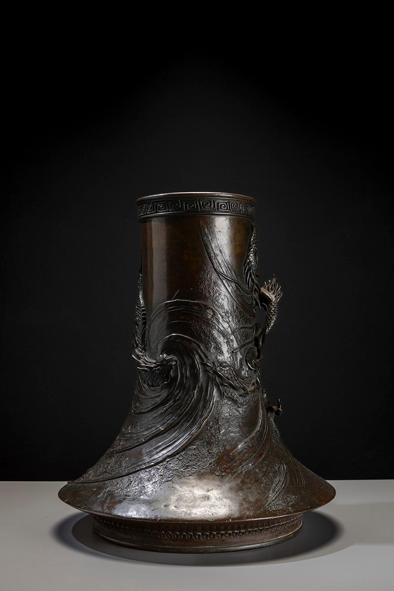 Vase monumental en bronze à patine brun foncé, représentant un dragon Ryu en haut-relief. Le vase a une forme cylindrique avec une base évasée qui rappelle le profil du mont Fuji.  

Le corps du dragon s'enroule sur toute la surface, qui est gravée