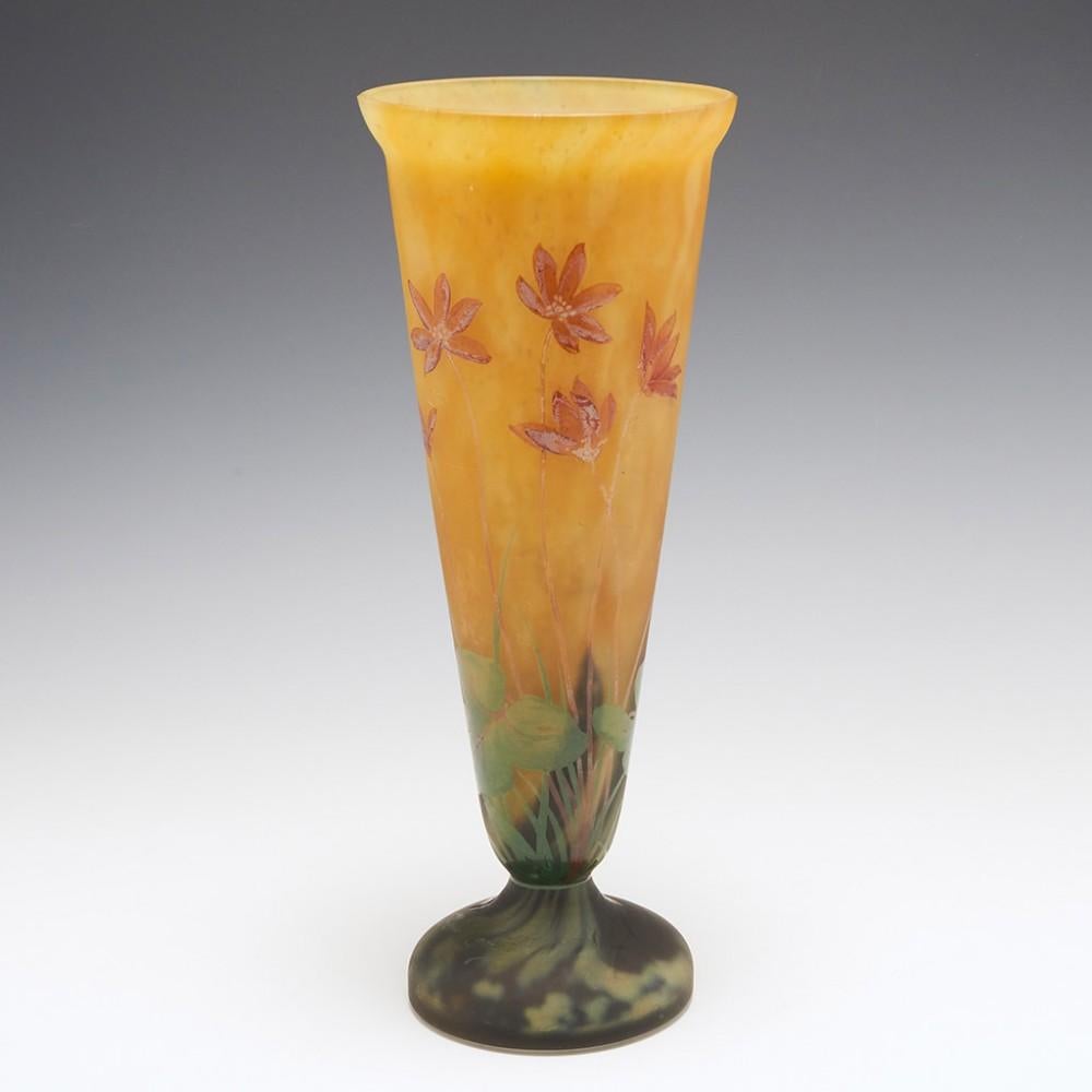 An Art Nouveau glass Mado Nancy Daum vase c1925 made at Daum's manufactory at La Belle Etoile, Croismare, France. Mottled orange and lemon ground enamelled in puce orange and green. The foot cased in satin finish clear glass. The bowl is decorated