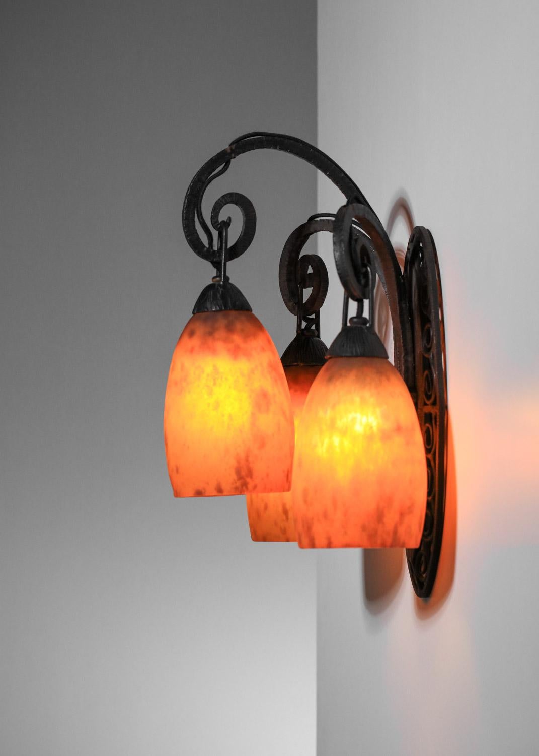 Beautiful French art deco wall sconce from the 1930s by Daum Nancy. Wrought-iron structure with fine manufacturing details (scrolls, decorative cabochons, etc.). Orange speckled glass shade. Very fine vintage condition, with traces of age and use