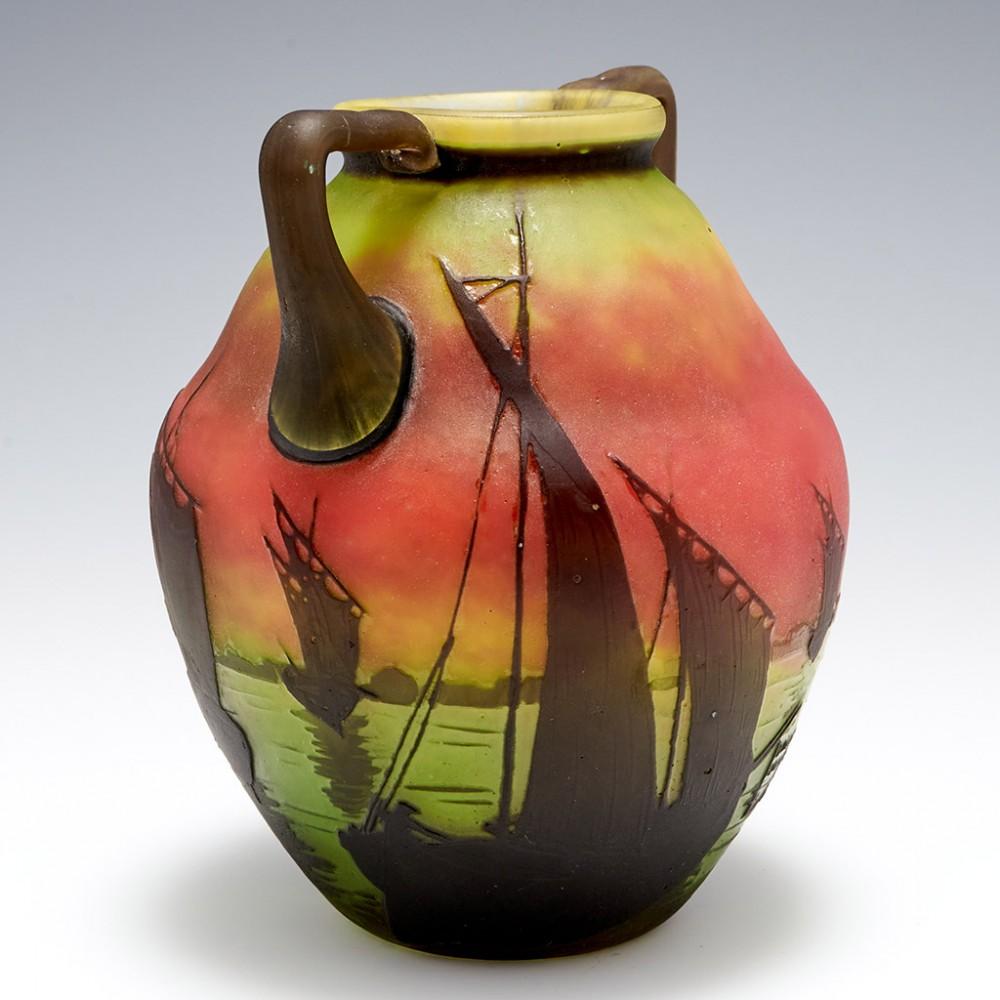 A Daum twin handled 1910 cameo glass vase of sailboats at sunset. Originated in France, with internal 'intercalaire' dense mottle toning from green through to yellow to orange.