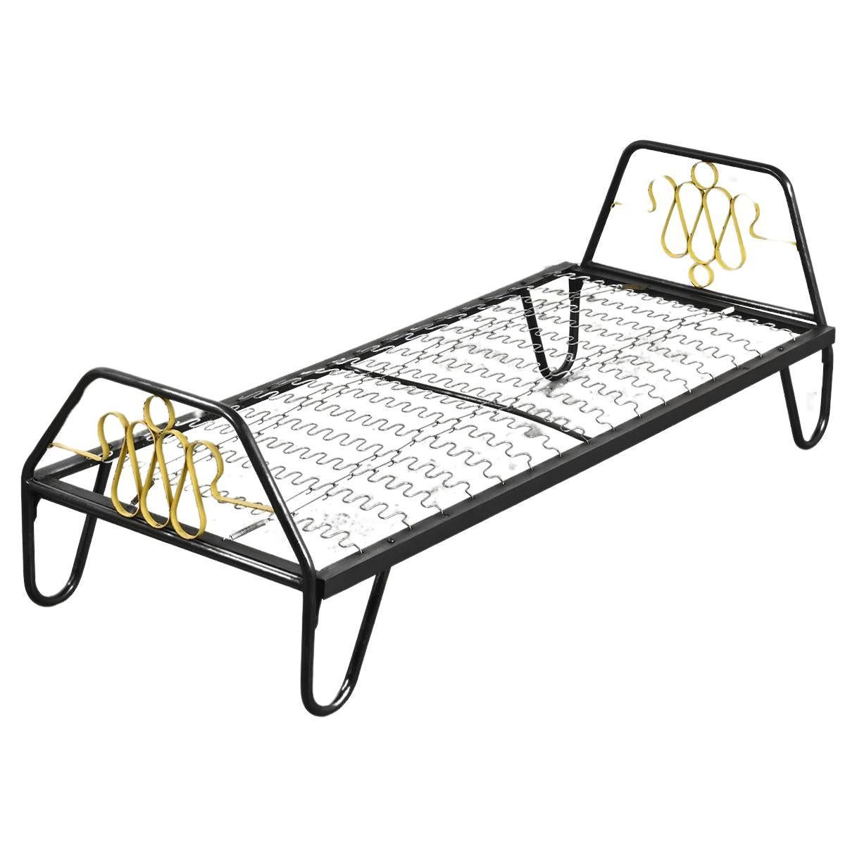 Letto da giorno con base tubolare in metallo laccato nero, caratteristica del lavoro del designer francese Jacques Hitier, con testiera e pediera ornate da volute laccate di giallo.

Materasso e bolsters sono disponibili su richiesta e con un