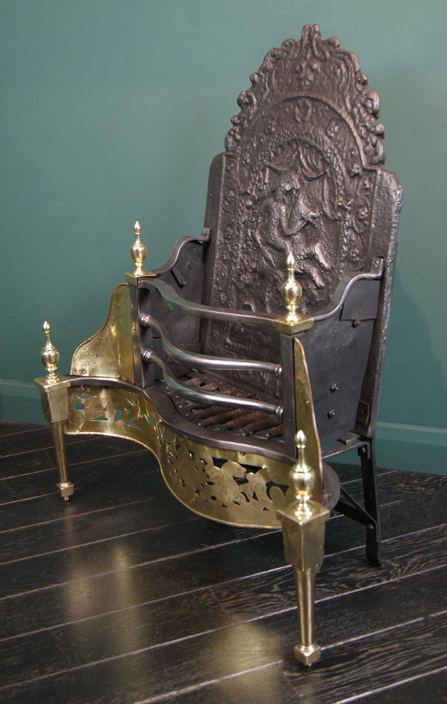 A decorative brass serpentine fire grate with shaped polished fire bars over an engraved and pierced fret. Tulip finials sit over column legs with plinth feet, rivet-work fire grill on traditionally constructed rear elements. The fire back depicting