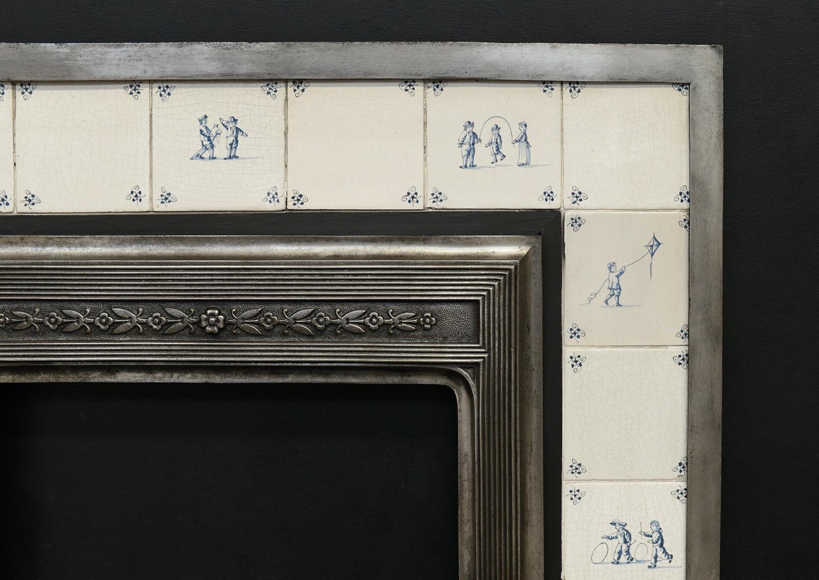 A decorative cast iron fireplace insert with Delft tiles. The shaped front bars with reeding and foliage embellishments. Ceramic Delft tiles surrounding, featuring children at play. English, circa 1900. 

Width At Front:	970 mm      	38 ¼