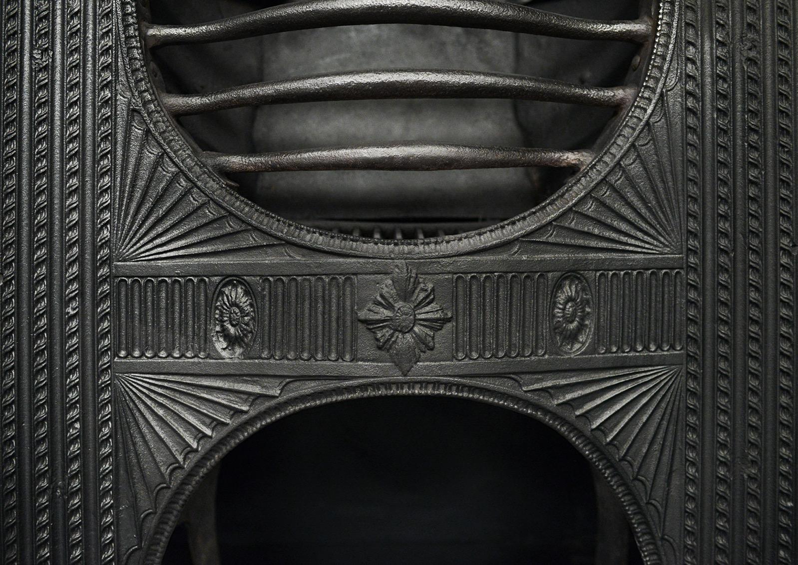 Una parrilla decorativa de hierro fundido con reloj de arena. La greca de fundición con patera y estrías, flanqueada por molduras de soga recurrentes. Barras delanteras arqueadas. Inglés, siglo XIX. 

Anchura Delantera:	838 mm      	33