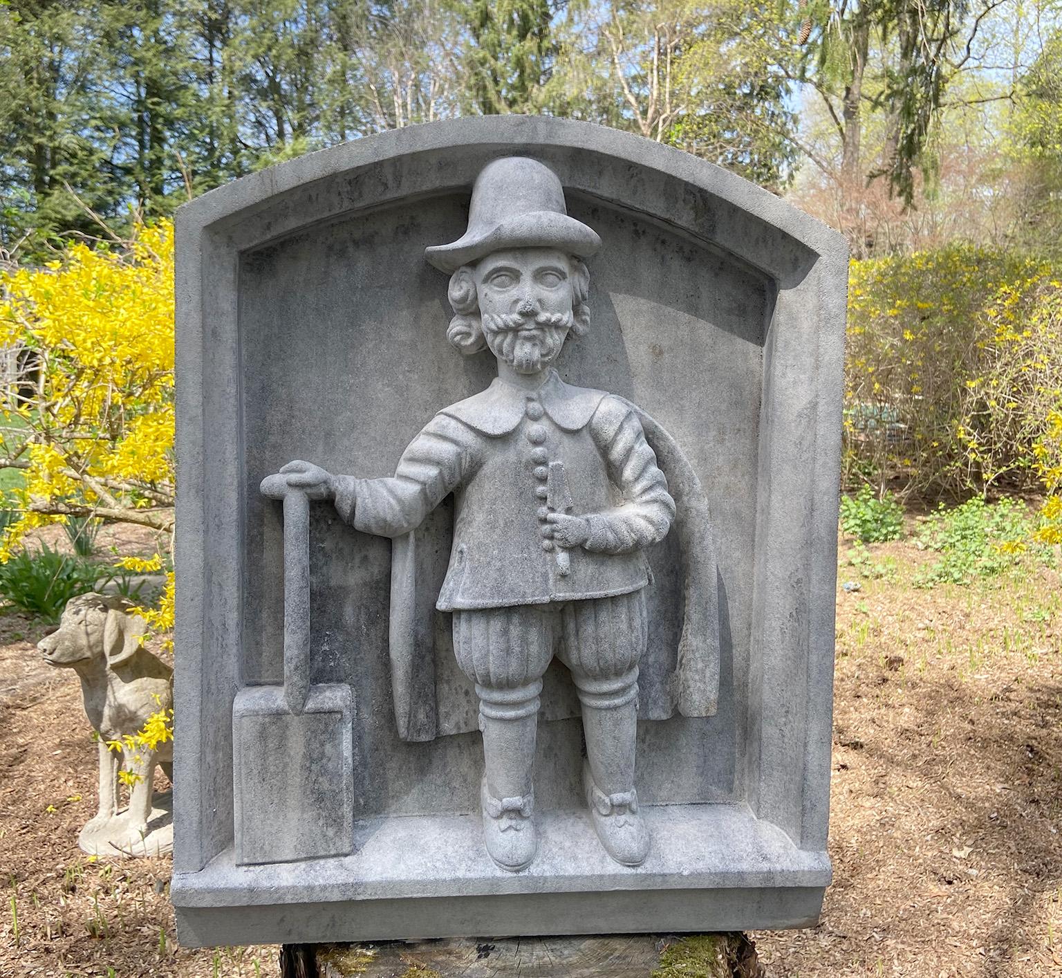 Plaque murale en pierre de composition avec sommet arqué représentant le botaniste et jardinier John Tradescant the Younger, debout en costume du XVIIe siècle, une bêche dans la main gauche et une pelle dans la main droite, par le fabricant