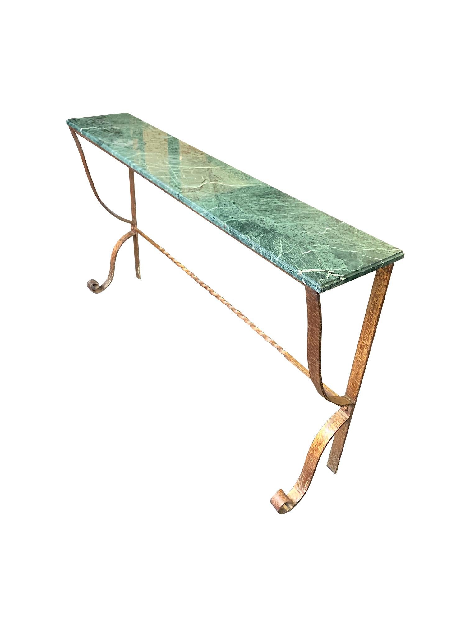 A decorative Spanish 1950s console with hammered and scrolling wrought iron gilt legs and frame with a green and white bevelled marble top.