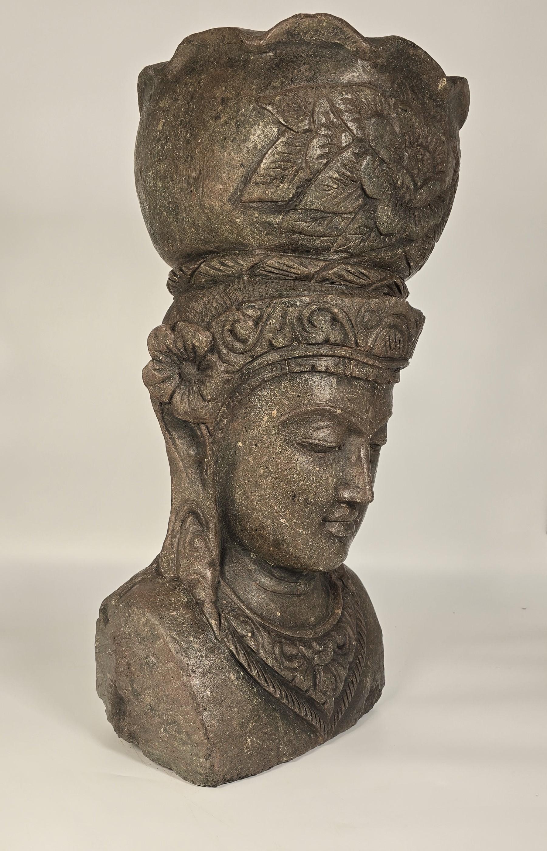 This life sized and well carved Raj period Indian bust depicts a female goddess or deity. It is hand carved from a single large piece of stone which is naturally greenish in colour, with small white fragments, which are most likely pieces of
