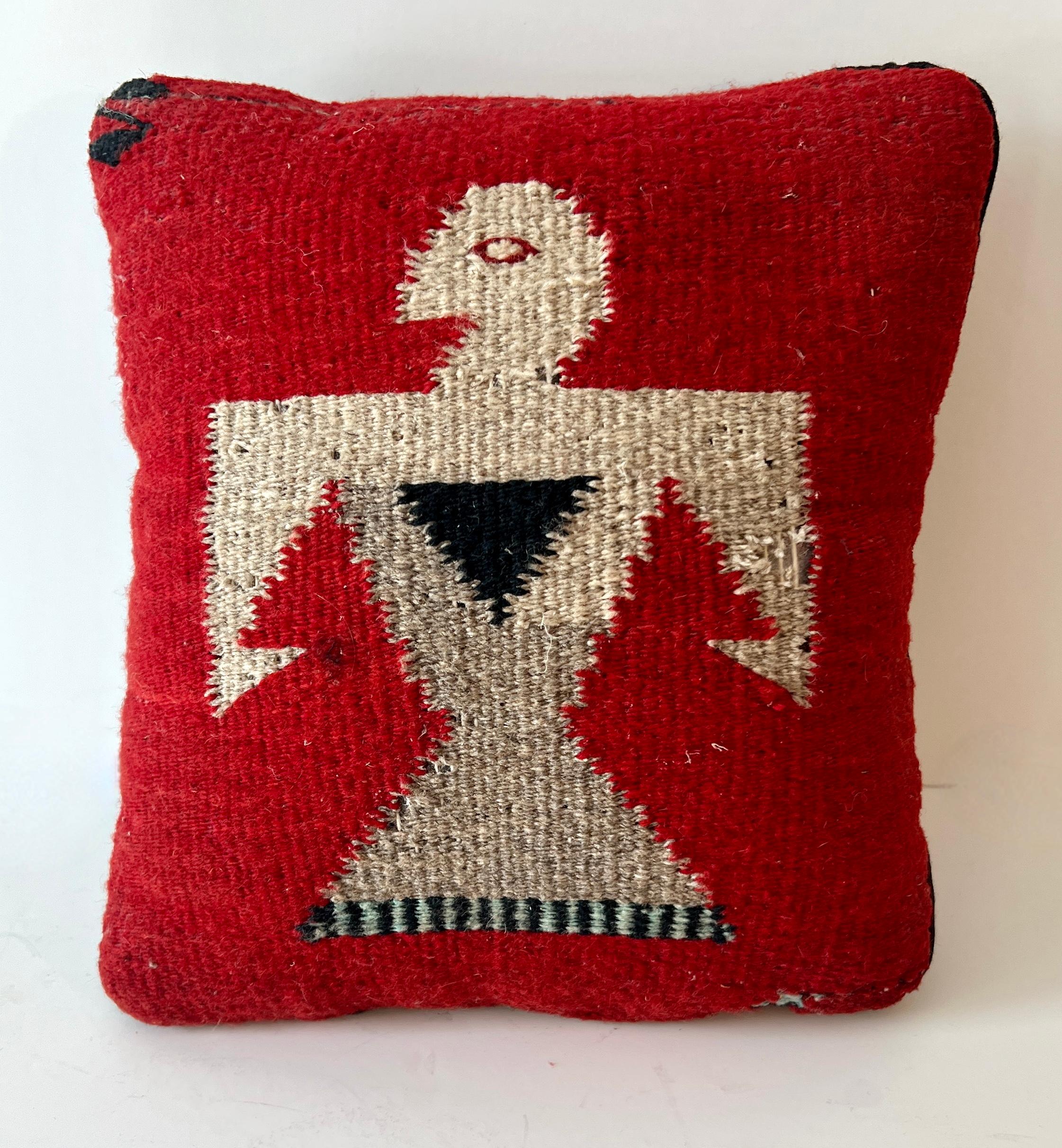 Almohada hecha de una pesada amenaza tejida / hilo en un campo de color rojo con un Pájaro o Águila representado en la parte superior.  El cojín es ideal como pequeño cojín de acento sobre un banco o con otros cojines del mismo curso.

Podría ser un