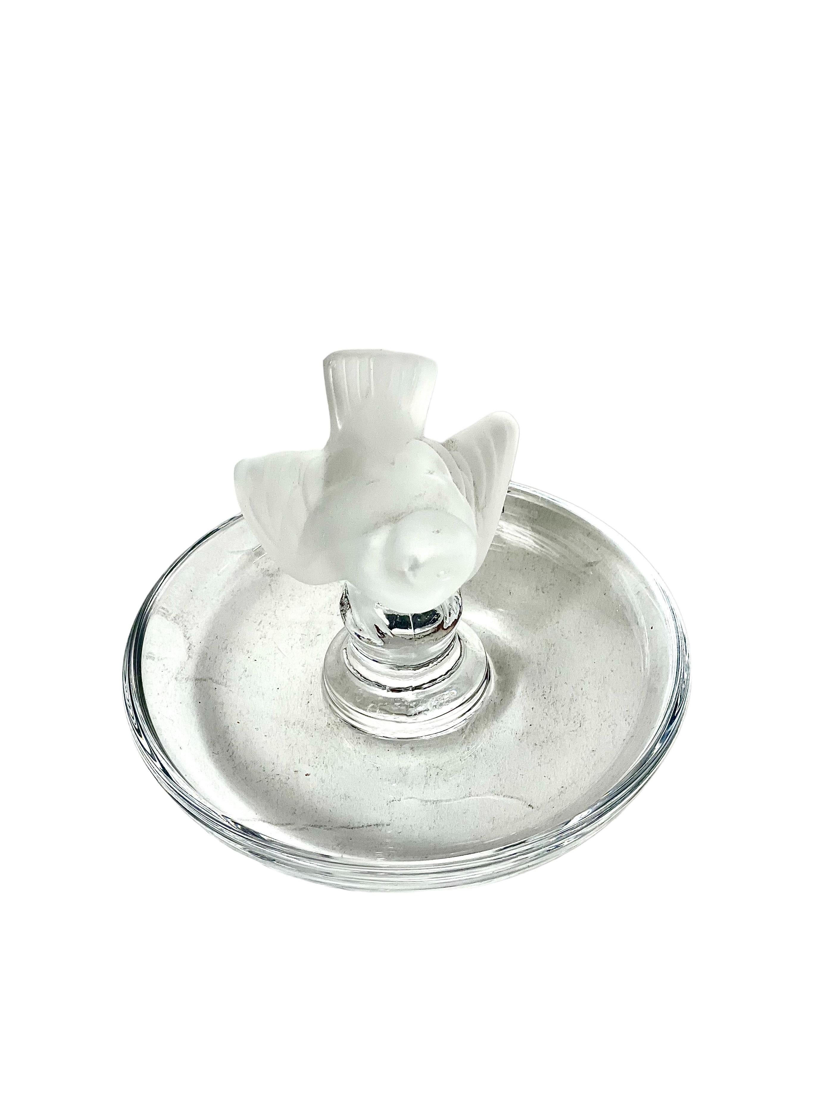 A delicate crystal ring dish surmounted with a frosted sparrow, from the renowned crystal and glass design brand, Lalique. This very pretty and iconic dish offers an elegant yet practical place to store favourite pieces of jewellery and small