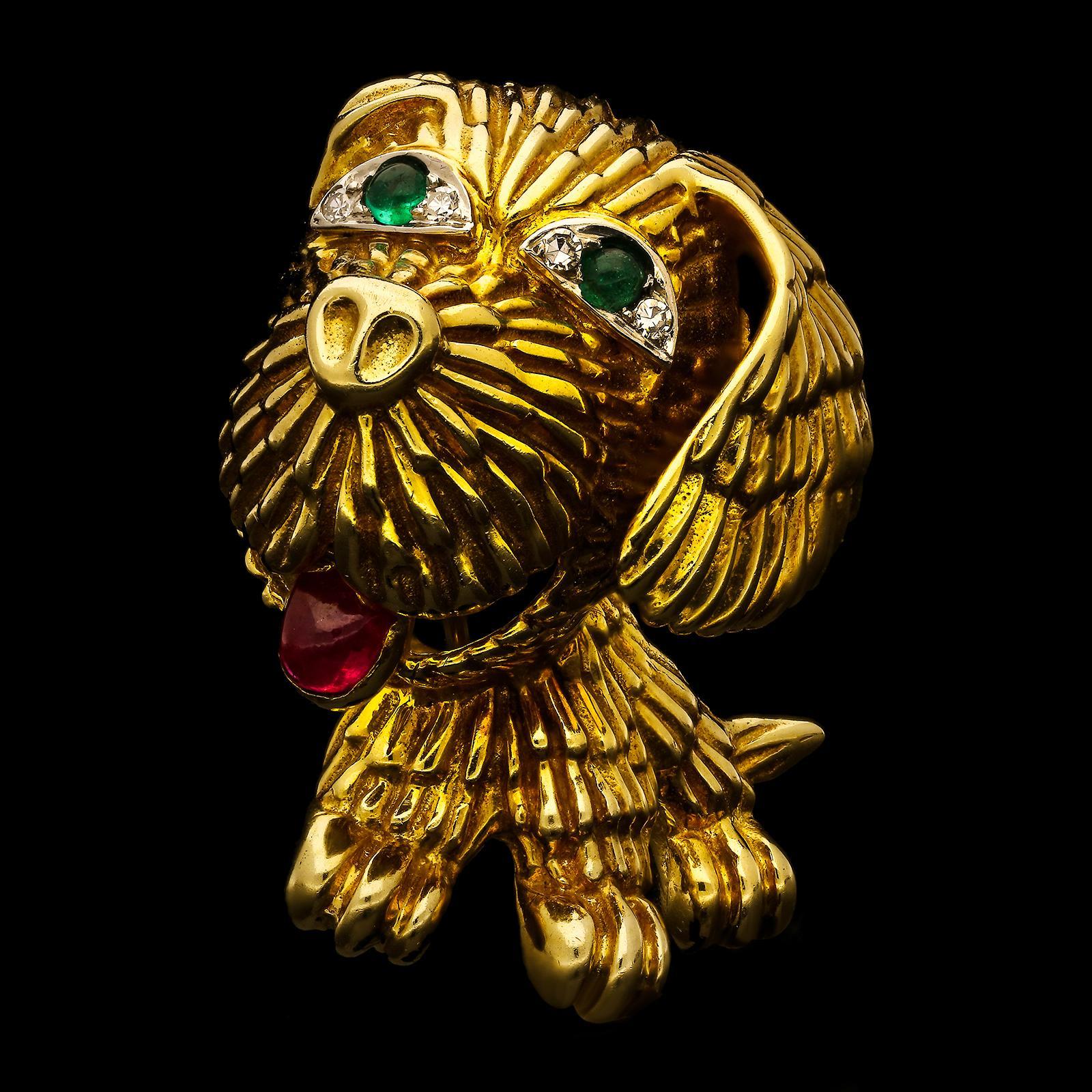 A delightful 18ct gold and gemstone brooch by Van Cleef & Arpels c.1960s, finely modelled as a three dimensional little dog in seated position with large floppy ears and textured fur formed from gold wire, the eyes set with a cabochon emerald and