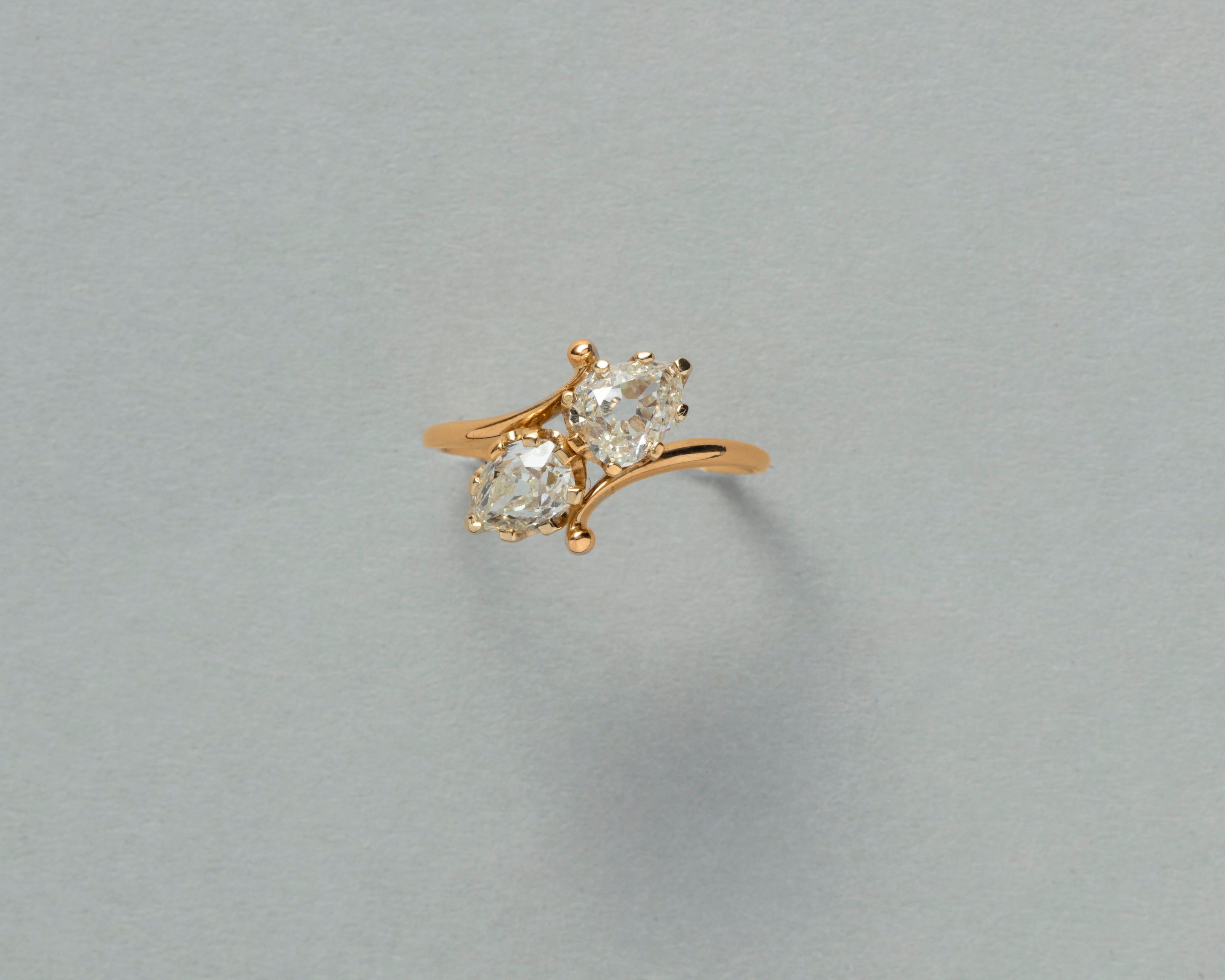 Ein französischer Toi et Moi-Ring aus 18 Karat Gold mit zwei Diamanten im Birnenschliff, die elegant von zwei Locken gehalten werden. Die Diamanten sind in acht Zackenfassungen gefasst.

Gewicht: 2,13 Gramm
Ringgröße: 17,25 mm / 7 US
Breite: 0,85 -