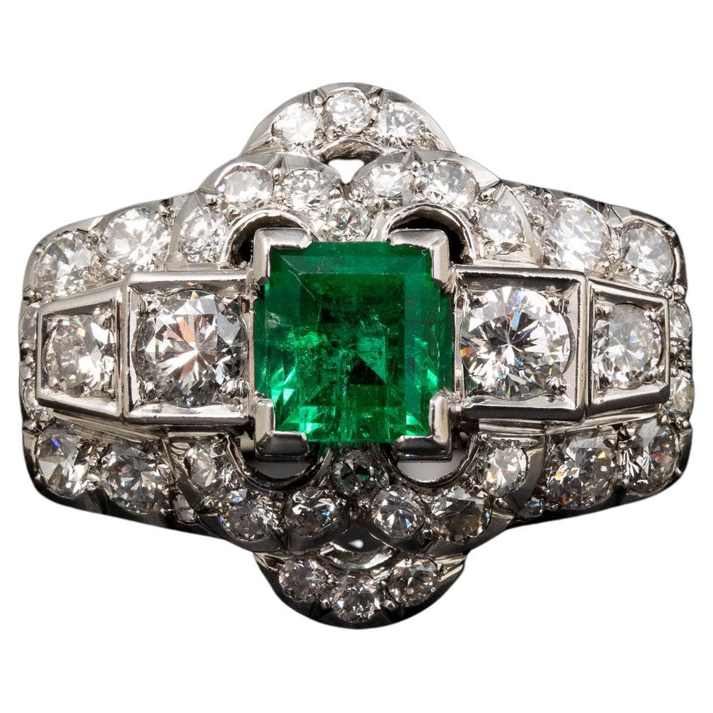 A diamond and platinum ring, set with a rectangular shaped emerald