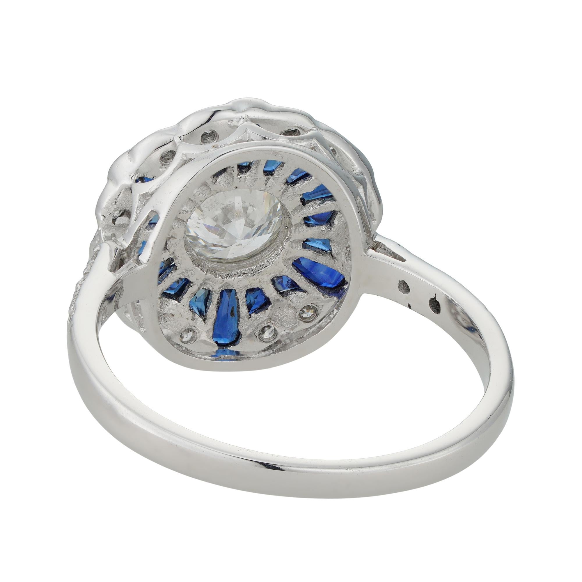 Ein Diamant- und Saphir-Cluster-Ring, der runde Diamant im Brillantschliff mit einem Gewicht von 0.70 Karat, begleitet von einem IGL-Zertifikat, das besagt, dass er von der Farbe H und der Reinheit VS2 ist, umgeben von Saphiren im Kaliberschliff,