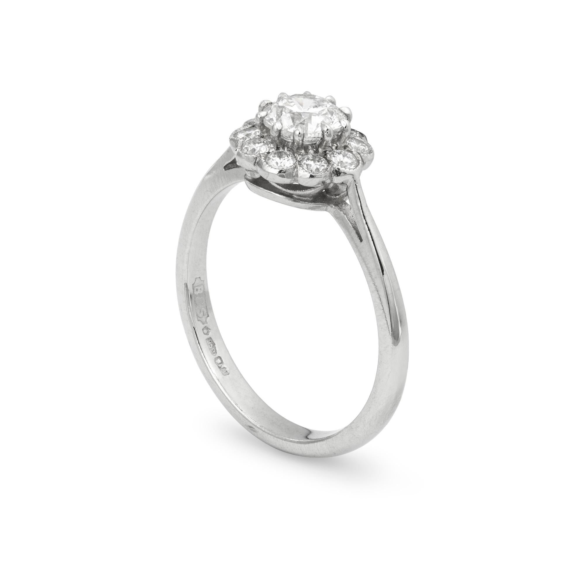 A diamond cluster ring, the central round brilliant-cut diamond, weighing 0.50ct, claw set within a border of ten smaller round brilliant-cut diamonds, weighing a total of  0.20ct, millegrain set, all to a platinum mount with tapering shoulders,