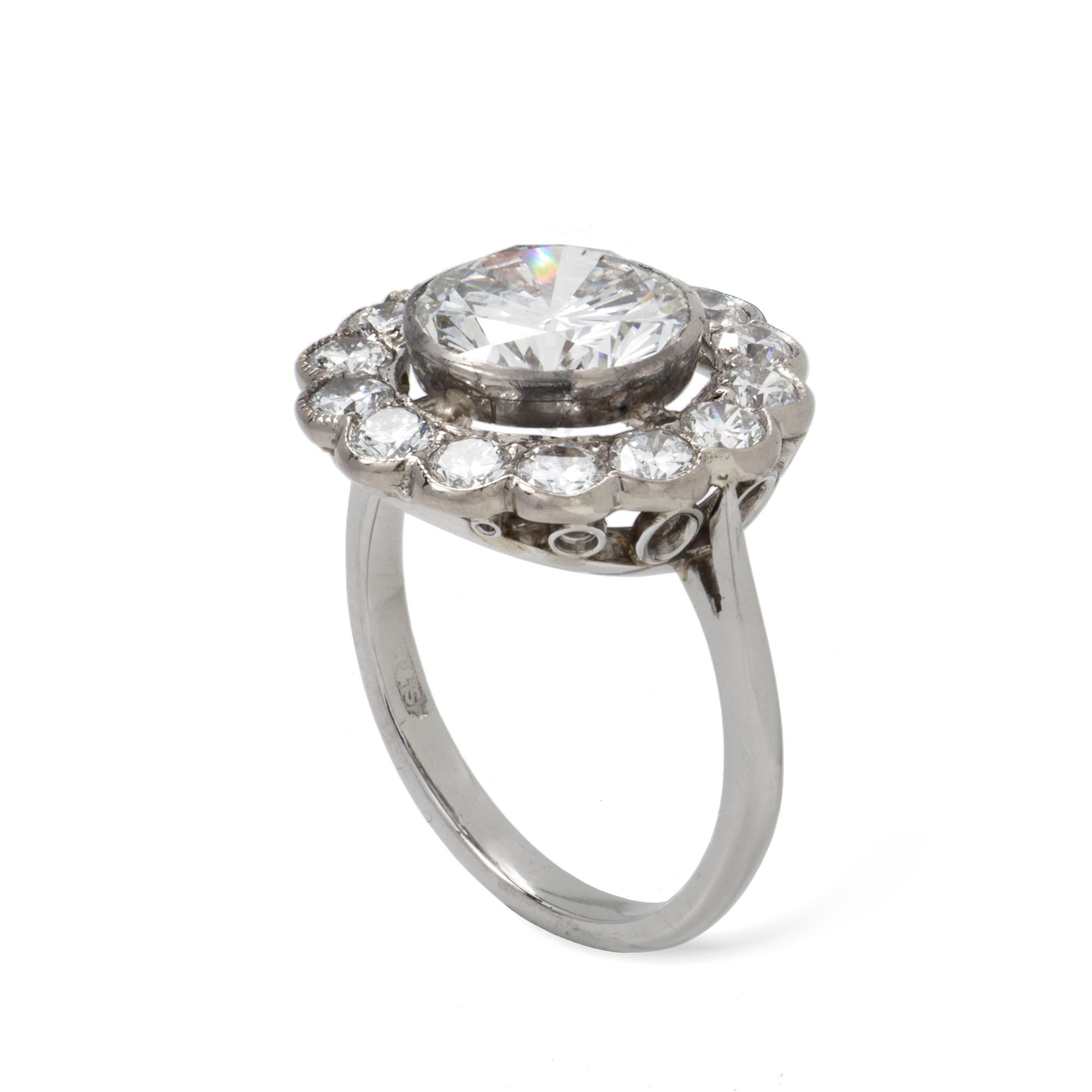 A diamond cluster ring, the round brilliant-cut diamond weighing 2.66 carats, accompanied by EE Report stating to be of H colour VS1 clarity, rub-over set to the centre of a round brilliant-cut diamond-set cluster weighing approximately a total of