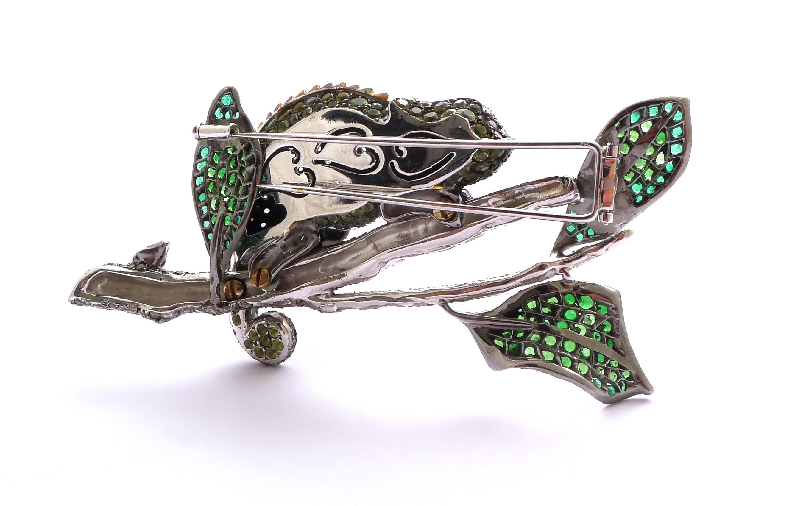 Modelled as a cameleon on a branch with leaves, set throughout with round emeralds, peridots, aquamarines, tsavorite garnets and diamonds, the eye as a cabochon ruby

Mounted in silver and 18K white gold

- 389 round diamonds: 13.83 ct total
- 247