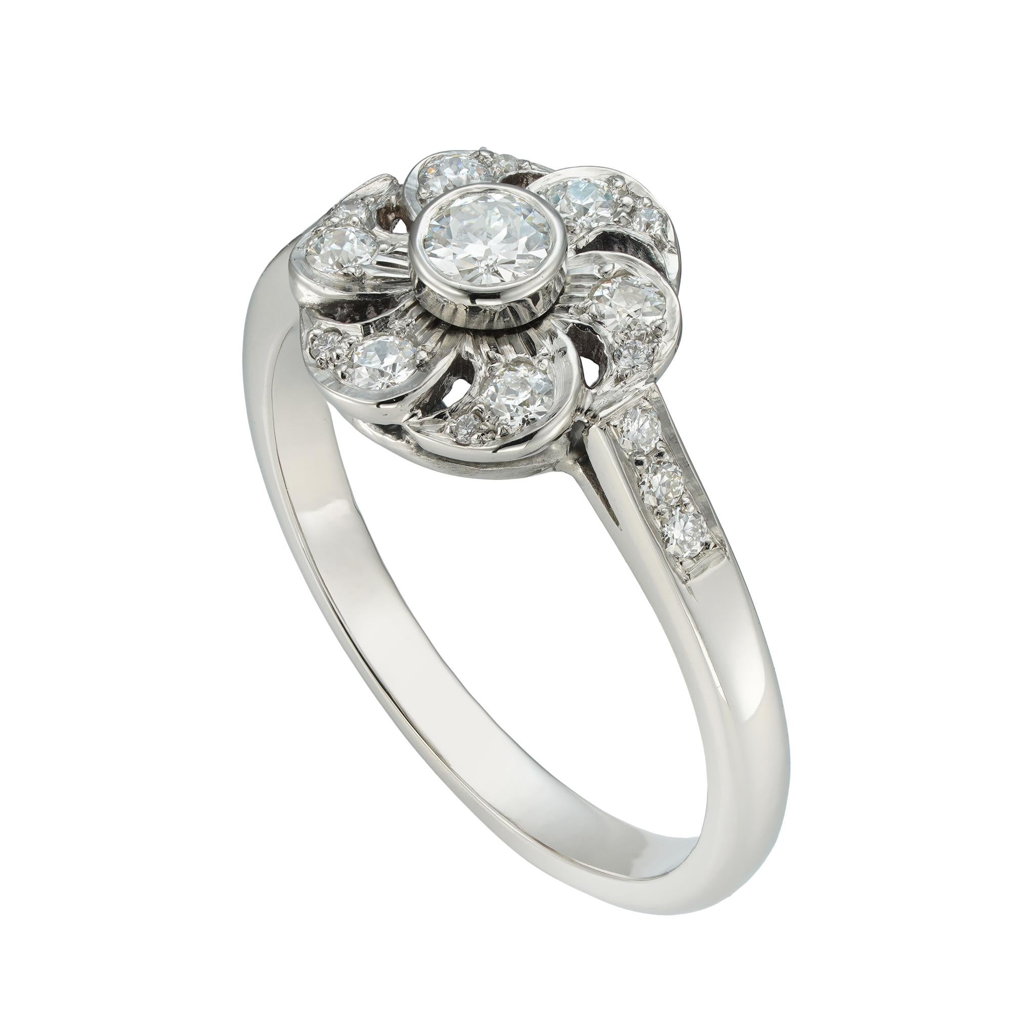 Ein diamantbesetzter Blumenring, in der Mitte ein Diamant im Altbrillantschliff mit einem Gewicht von 0,15 Karat, umgeben von sechs Blütenblättern, die mit kleinen Diamanten im Altschliff verziert sind, auf diamantbesetzten Schultern, die kleineren
