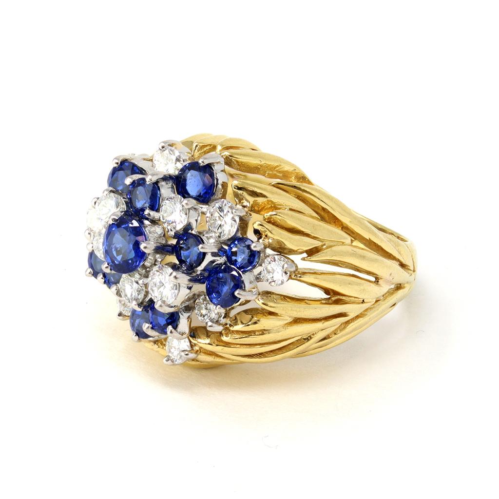 The striking diamond and sapphire cluster ring is circa 1960. The full cut round diamonds have an estimated weight of 0.96 carats of G color and VS clarity. The round sapphires display great color and have an estimated weight of 1.63 carats. The