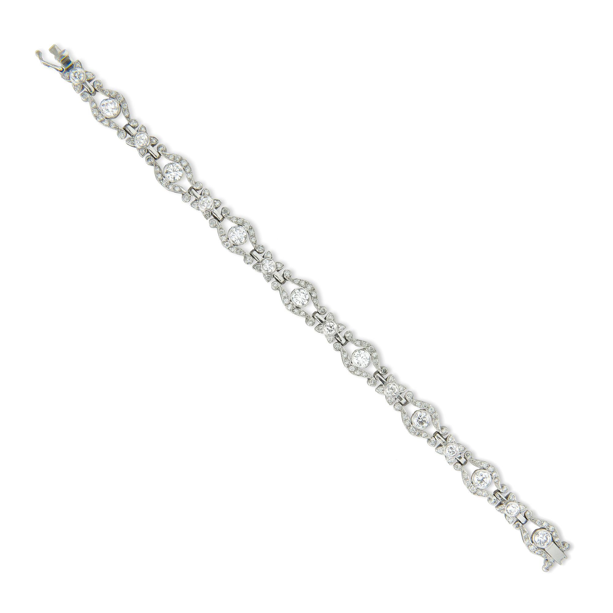 Brazalete engastado con diamantes, ocho eslabones calados con diseño de volutas, cada uno con un diamante redondo talla brillante engastado en el centro, conectados por ocho eslabones más pequeños en racimo engastados con diamantes, todos los