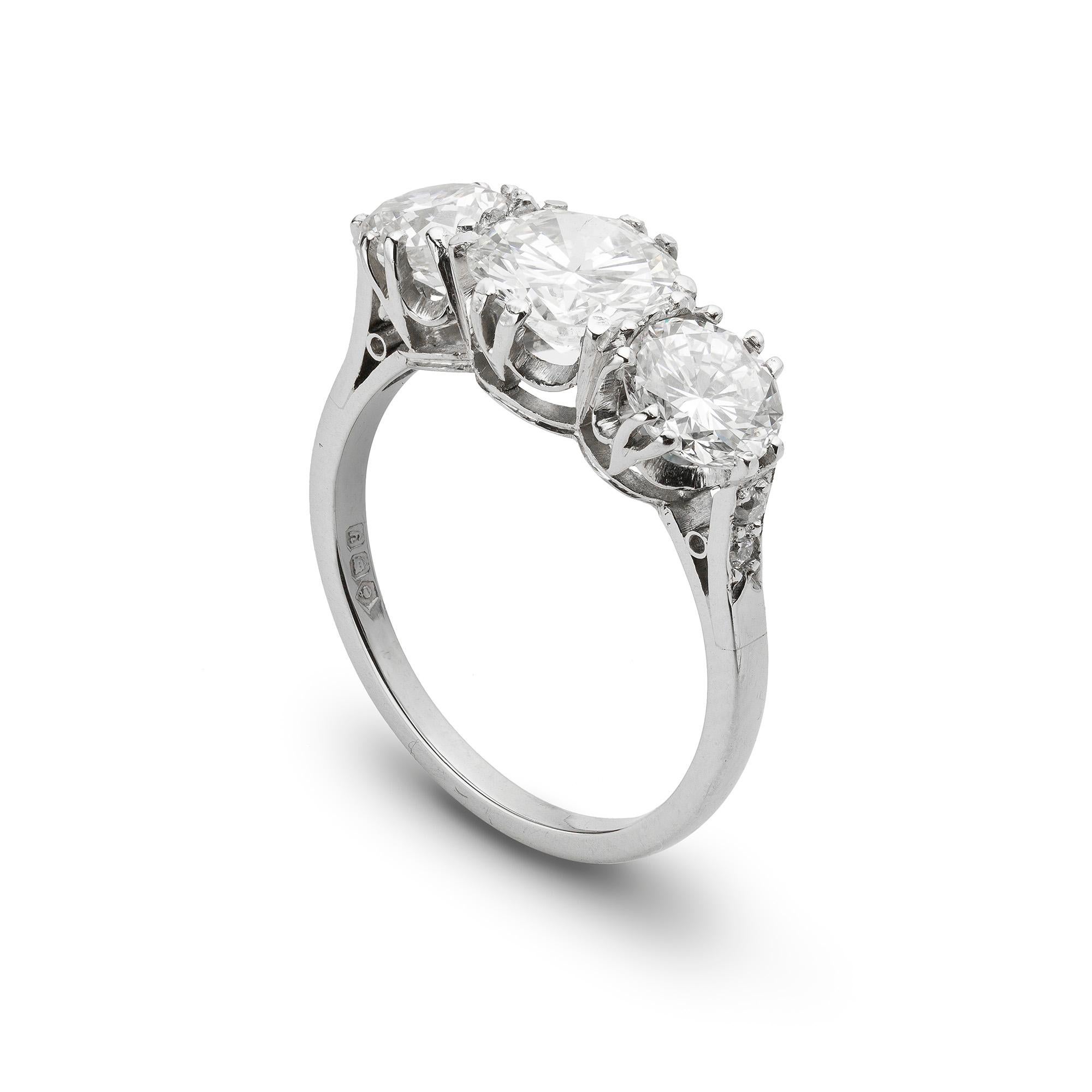 A diamond three stone ring, the central round brilliant-cut diamond weighing 1.05 carats and the outer diamonds a further total of 1.18 carats, split claw set to a platinum mount with diamond set chenier shoulders, hallmarked platinum London 1998,