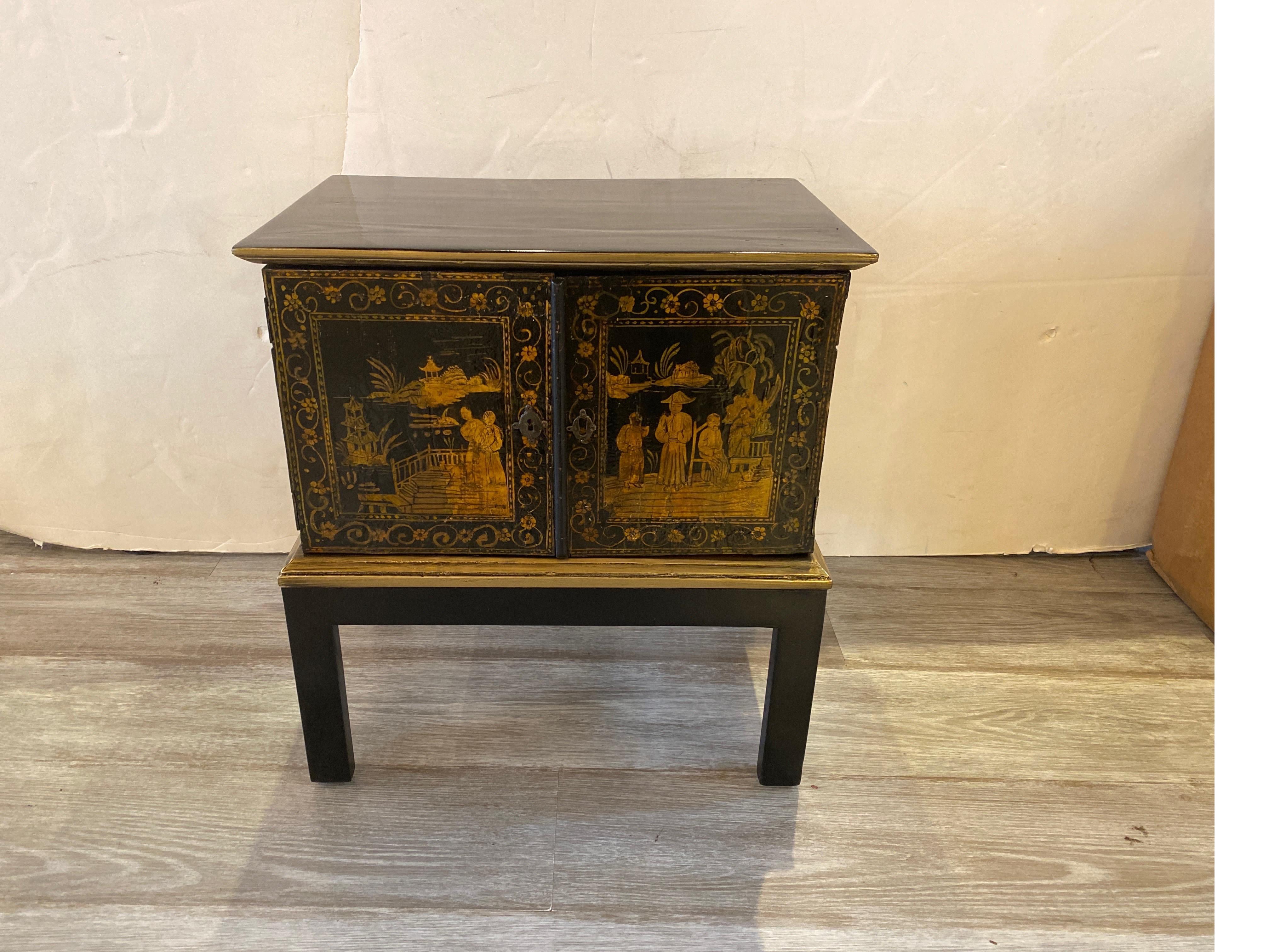 A diminutive black and gold lacquered Anglo-Indian spice cabinet. This is a small version, 18.75 inches tall, 17 inches wide, 11 inches deep. The chinoiserie hand painted doors with a black and gold case with doors that open to reveal small various