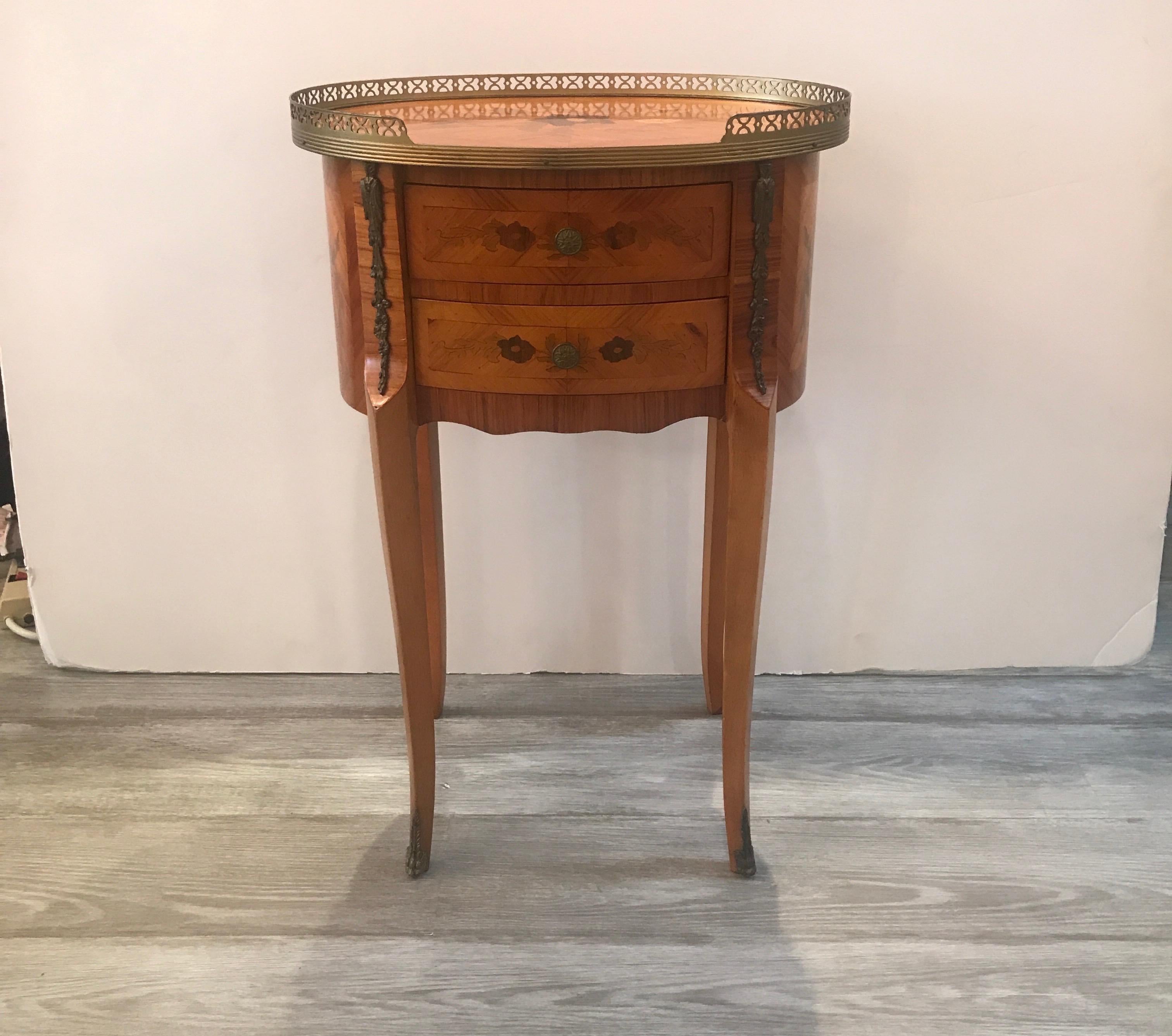 A beautiful inlaid oval side table with drawers. The reticulated gallery edge top with inlaid decoration on the top of satinwood, king’s wood and tulip wood. The inlay is repeated on the finished back with four gracefully curved legs.