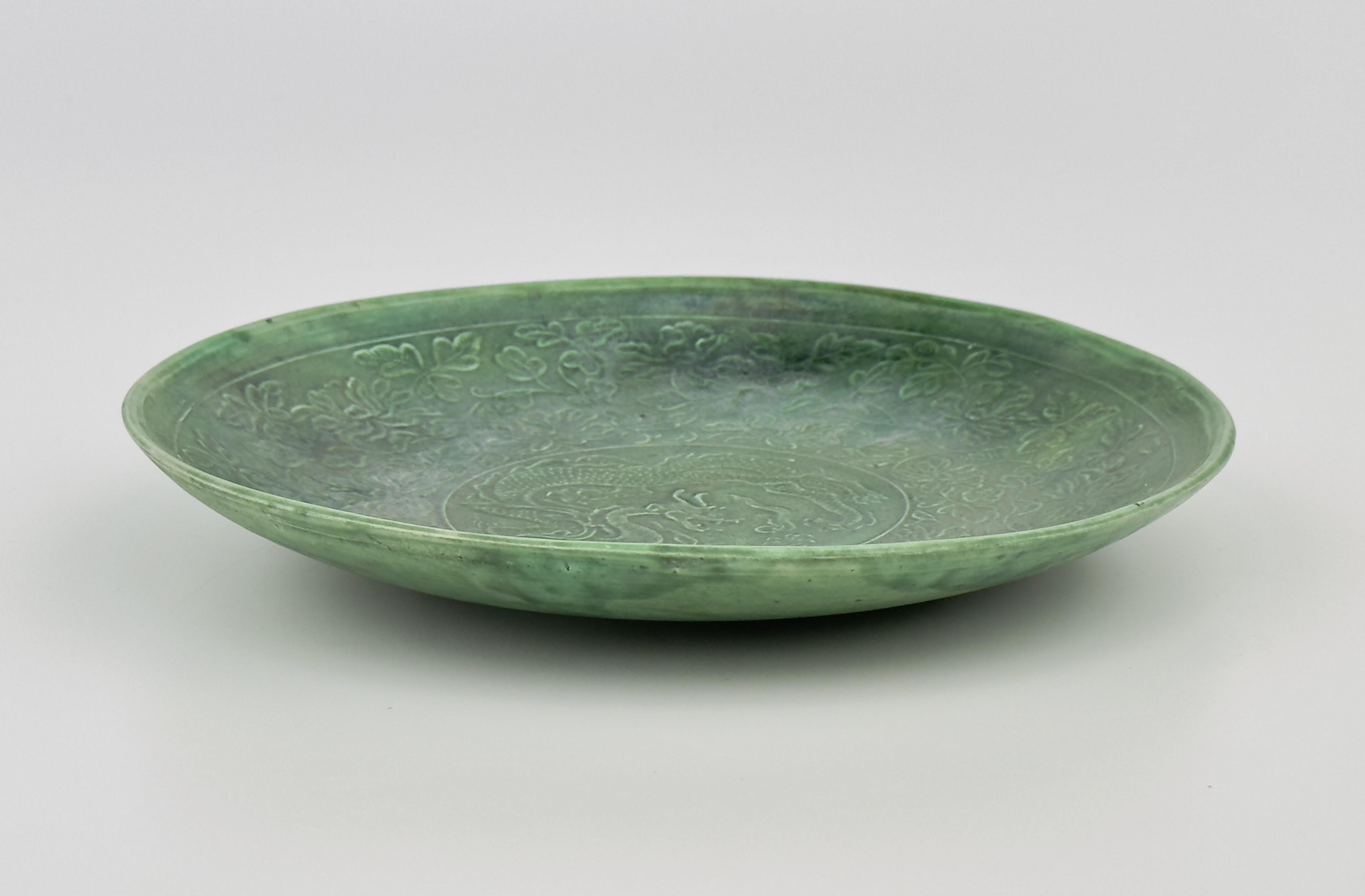 Diese grün glasierte Schale wurde mit viel Liebe zum Detail gefertigt, was das Können des Töpfers der Cizhou-Grün- und Ding-Ware unterstreicht. Seine zarte Form ist mit einem Drachen in der Mitte geschmückt. Das zentrale Drachenmotiv ist von einem