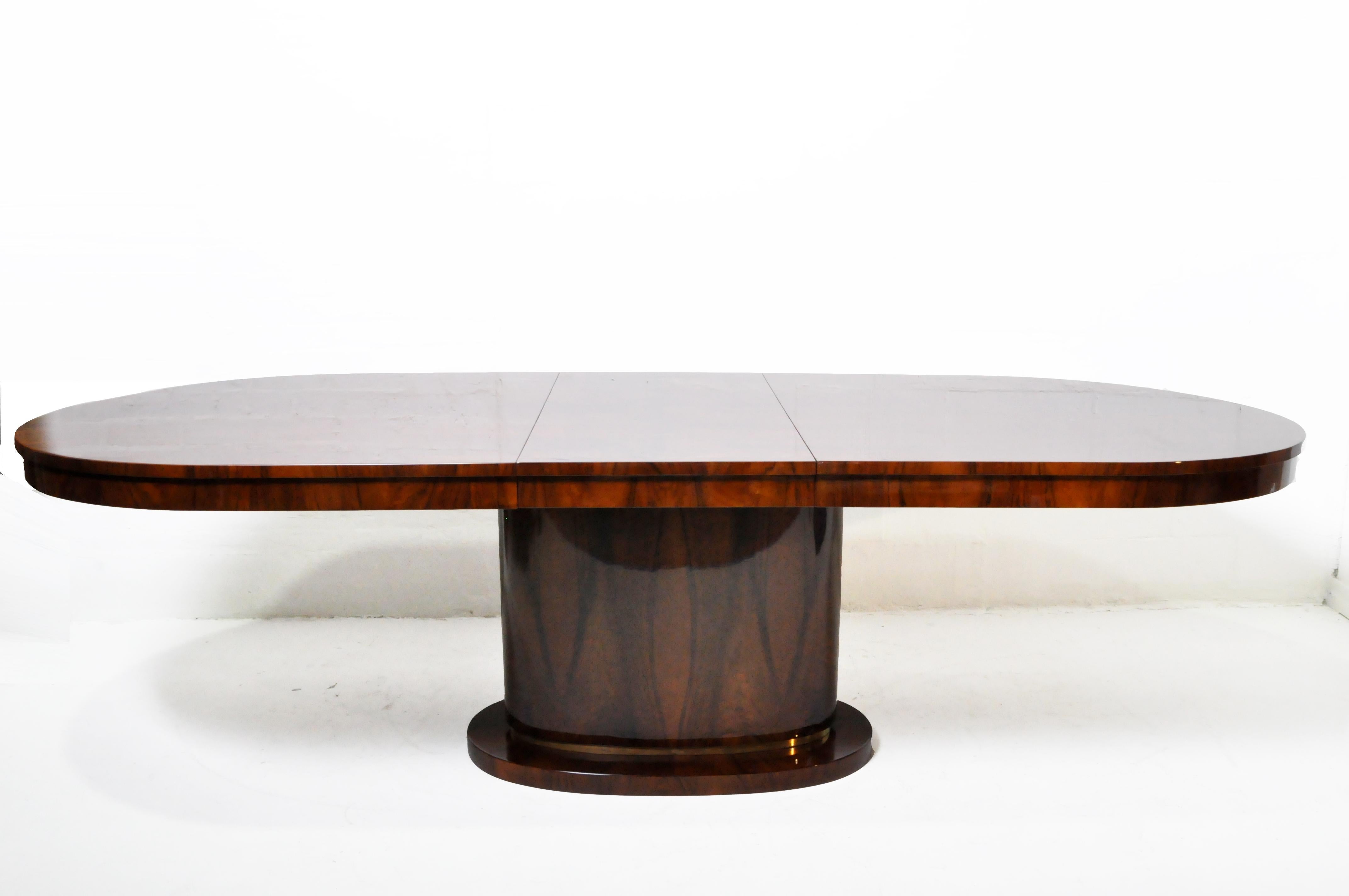 This striking Hungarian Art Deco table closely follows classic French Art Deco dining table designs from the 1930's. With its pedestal base, brass fittings and polished walnut veneer surface, the table has a nautical appearance. It comes with one