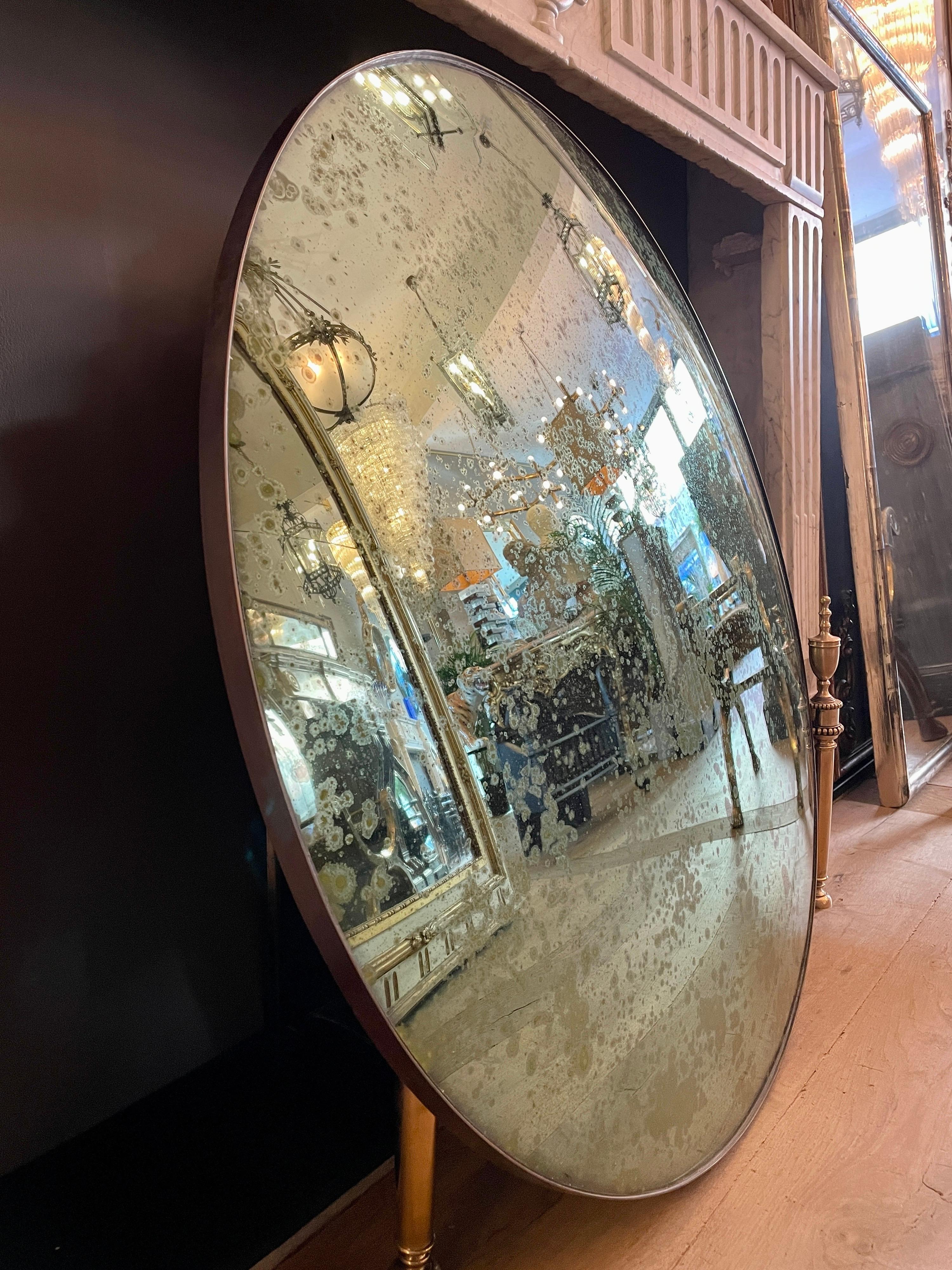A green distressed convex mirror with bronze patinated banded frame. Contemporary.
