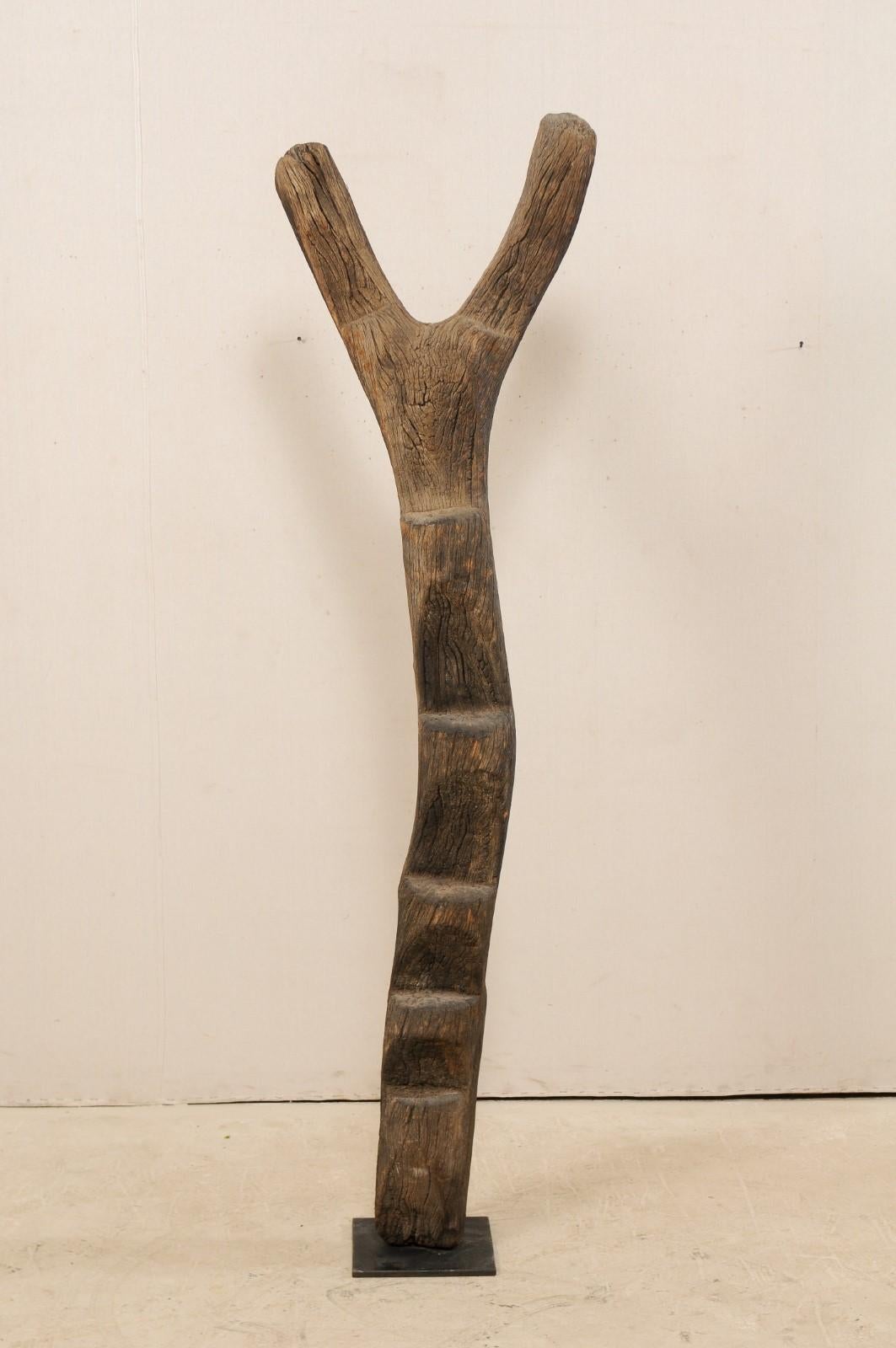 An early to mid-20th century Dogon tribe wooden ladder, on custom metal stand. This wooden ladder, which has been hand-carved from a single piece of wood, was used by the Dogon tribes people of the Bandiagara Escarpment region of Mali, was used to