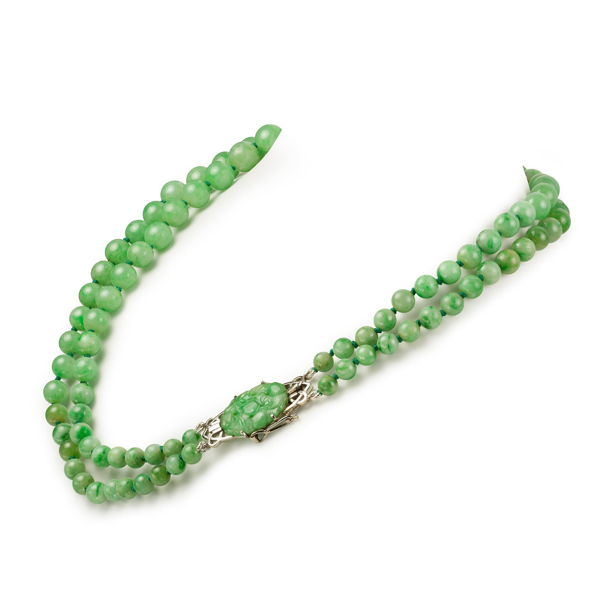 A double row jade necklace, both strands graduating from the centre measuring 5mm to 10mm, a total of one hundred beads, to a 14ct white gold jade carved clasp, length 31cm, stamped 14k, gross weight 73.6 grams.

A chic jade necklace. This necklace