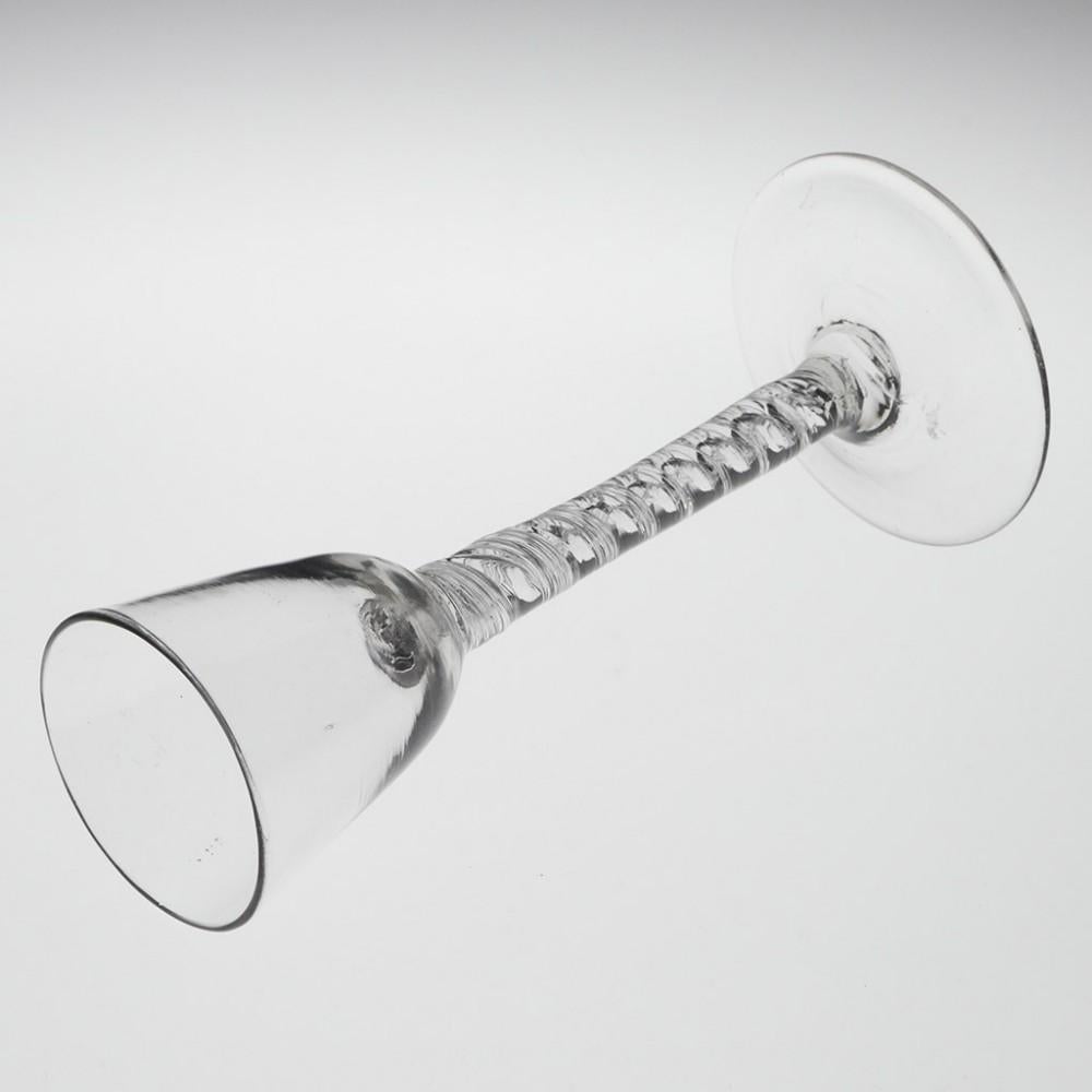 Double Series Air Twist Stem Weinglas, um 1750

Der zentrale Korkenzieher hat einen gleichmäßigen kreisförmigen Querschnitt. Die Fäden innerhalb des Spiralbandes sind eiförmig und haben ein versilbertes Aussehen, was auf die innere Brechung des